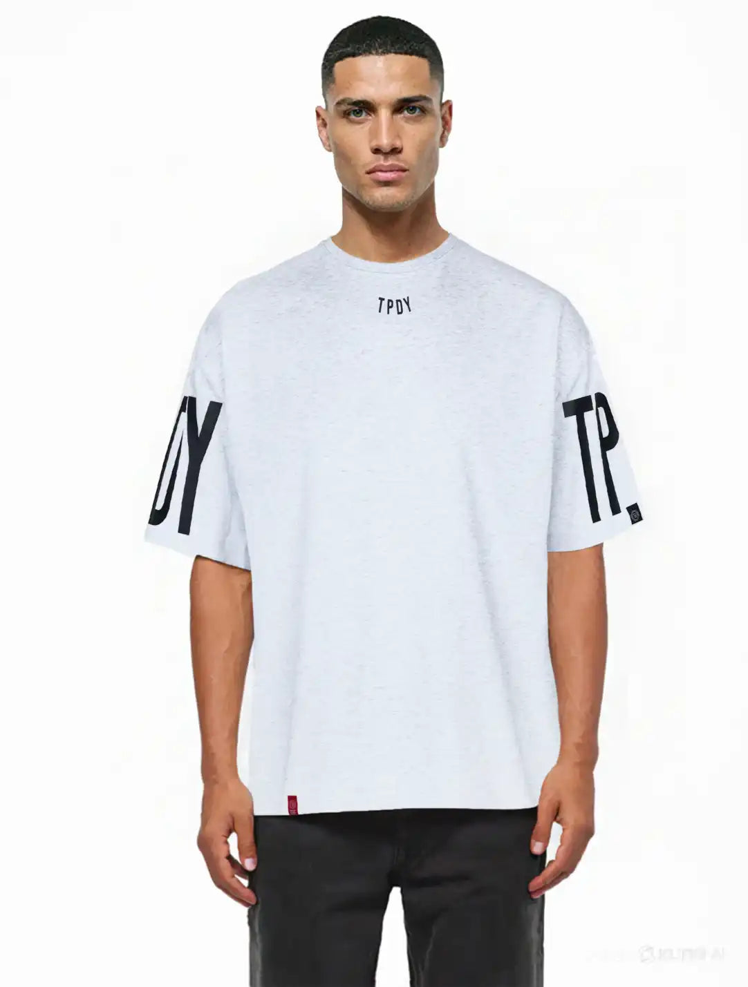 Ein Mann mit kurzen Haaren modelliert das Viktor Oversize-Herren-T-Shirt von trueprodigy. Dieses lockere, schwere Jersey-Shirt in Hellgrau hat schwarze TPDY-Prints auf dem Kragen und den Ärmeln. Er posiert vor einem schlichten weißen Hintergrund.