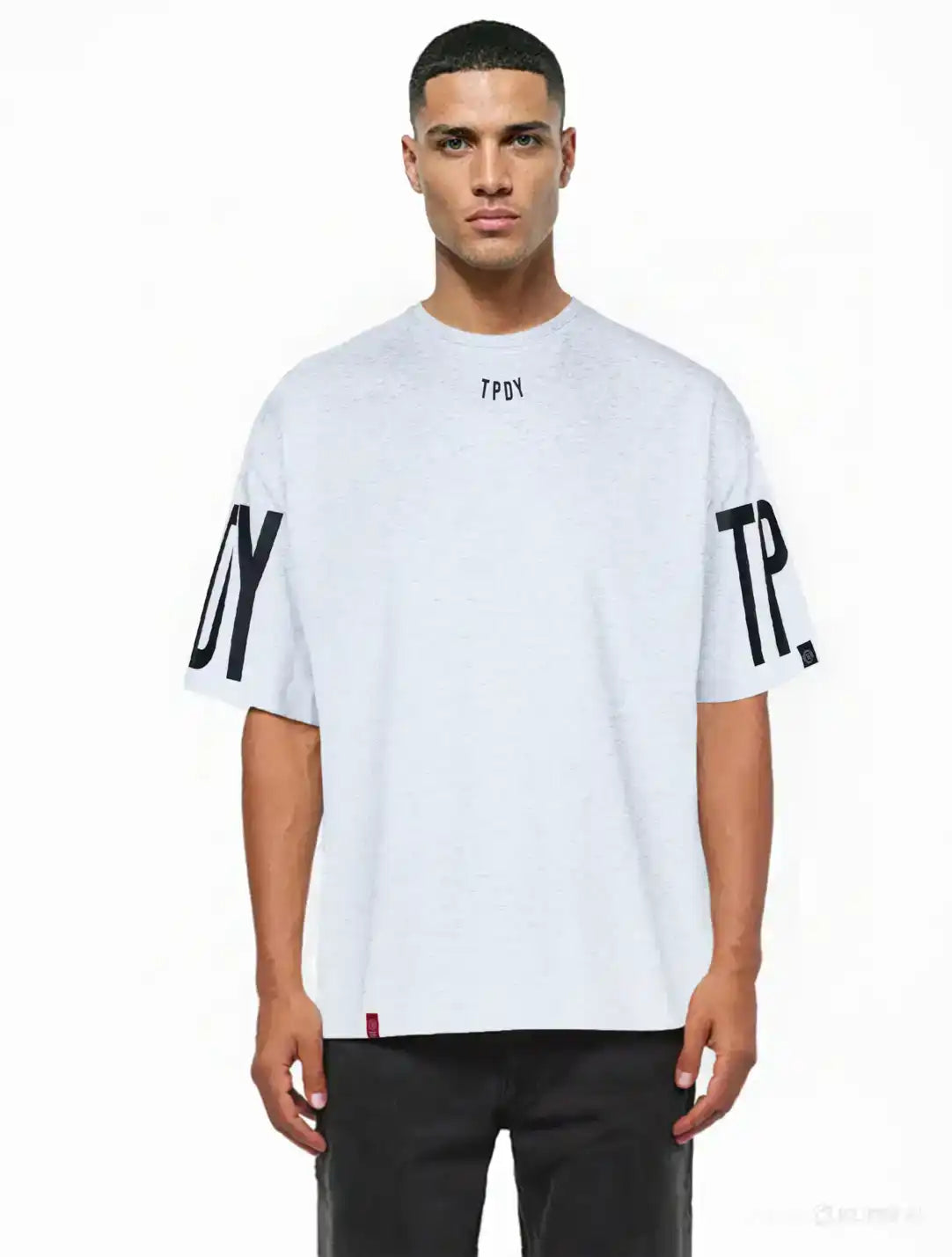 Ein Mann mit kurzen Haaren modelliert das Viktor Oversize-Herren-T-Shirt von trueprodigy. Dieses lockere, schwere Jersey-Shirt in Hellgrau hat schwarze TPDY-Prints auf dem Kragen und den Ärmeln. Er posiert vor einem schlichten weißen Hintergrund.