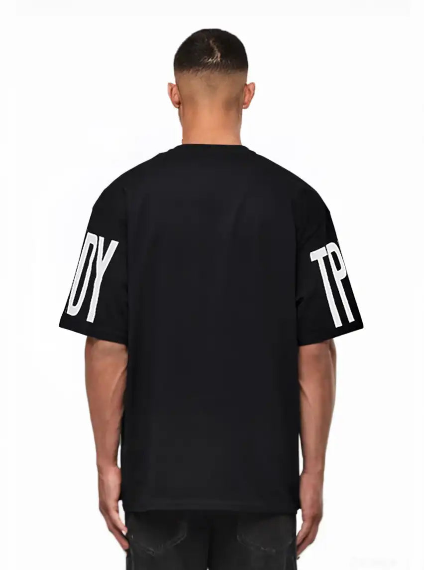 Ein Mann blickt von der Kamera weg und trägt das trueprodigy Viktor Oversize-Herren-T-Shirt mit schwerem Jersey-Stoff und großen weißen "TPD"- und "Y"-Ärmelaufdrucken vor einem schlichten weißen Hintergrund.