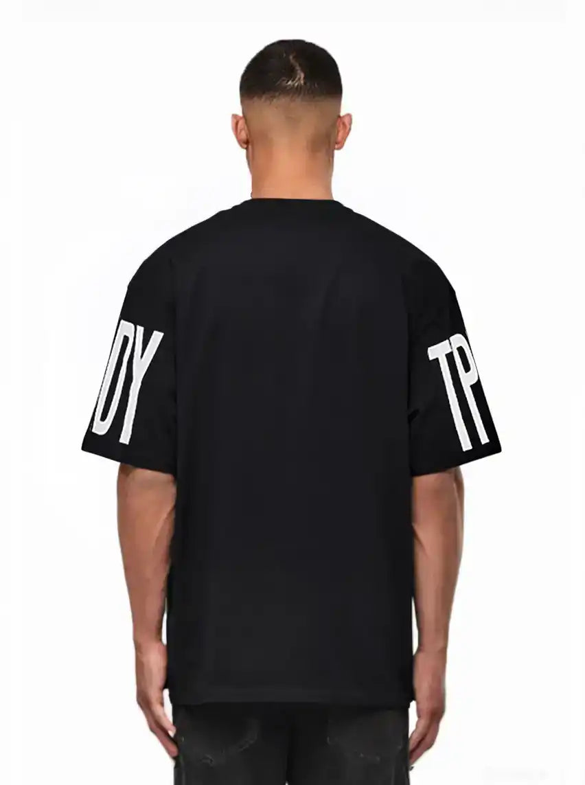 Ein Mann blickt von der Kamera weg und trägt das trueprodigy Viktor Oversize-Herren-T-Shirt mit schwerem Jersey-Stoff und großen weißen "TPD"- und "Y"-Ärmelaufdrucken vor einem schlichten weißen Hintergrund.
