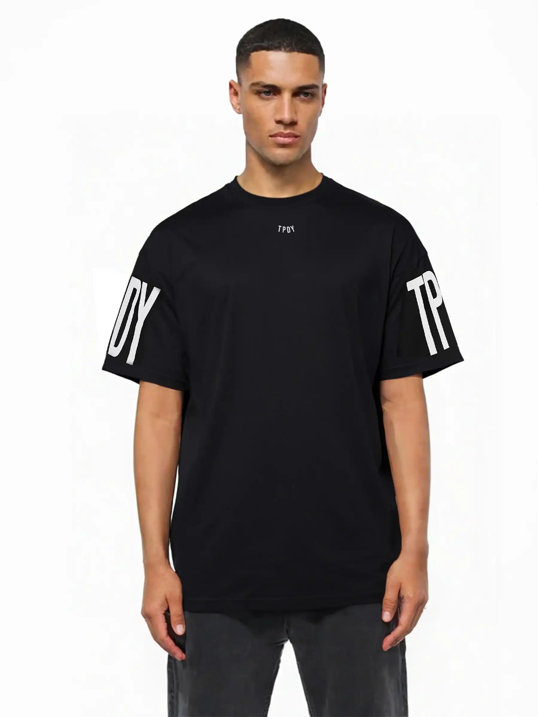 Ein Mann trägt das trueprodigy Viktor Oversize-Herren-T-Shirt mit weißen TPDY-Prints auf der Vorderseite und den Ärmeln vor einem schlichten weißen Hintergrund.