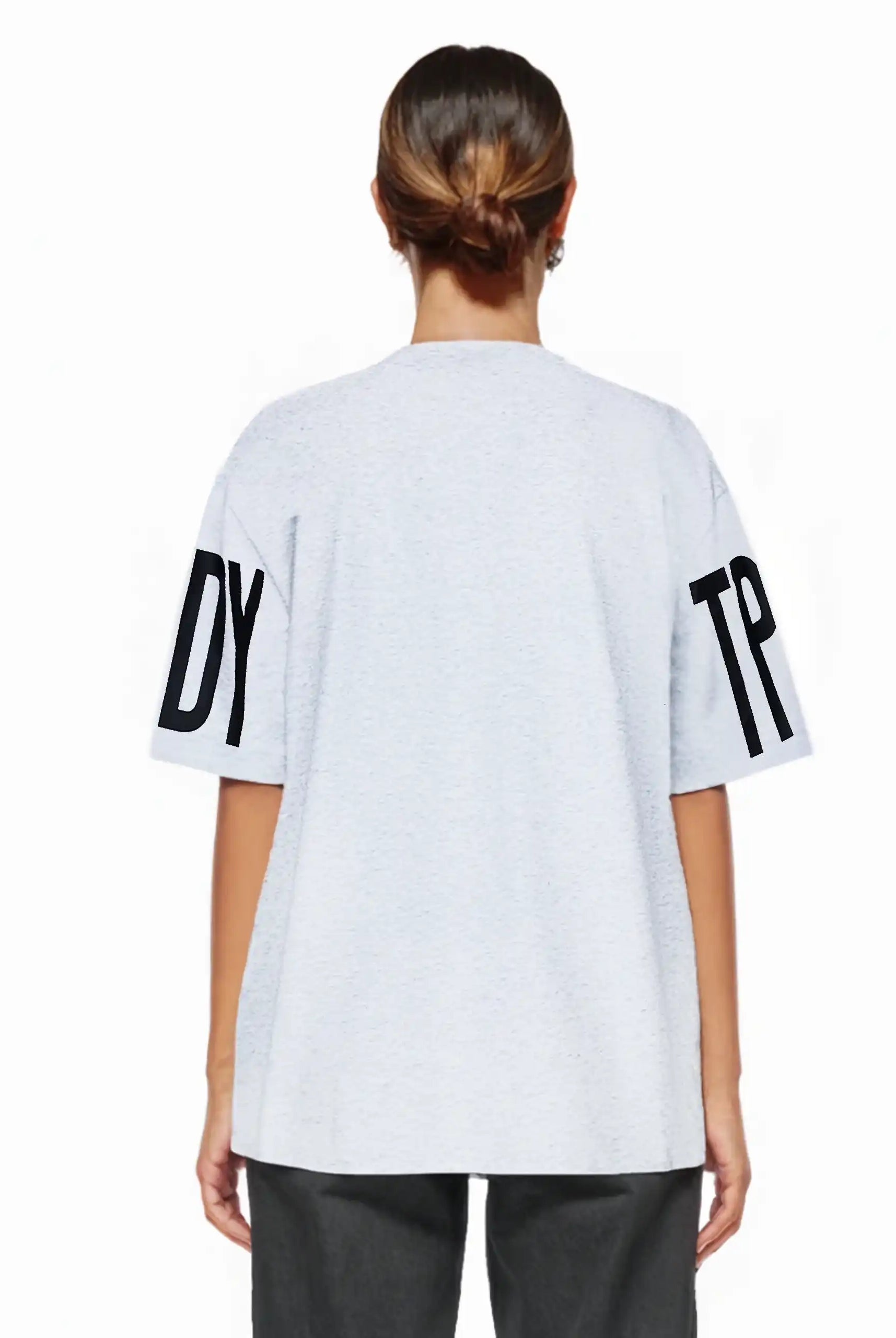 Eine Person steht mit dem Gesicht zur Wand und trägt das Viktor F Oversize-Damen-T-Shirt mit Ärmelprints und Frontprint unter dem Kragen von trueprodigy in Hellgrau, mit großen Ärmeldrucken, gepaart mit einer dunklen Hose. Die Haare sind zu einem tiefen Dutt gestylt.