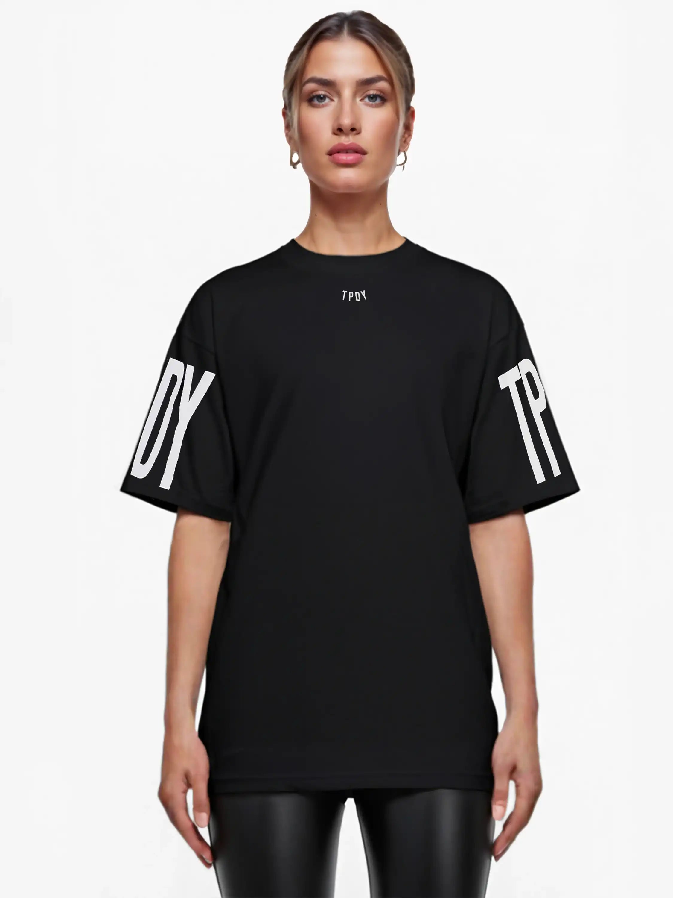 Eine Person blickt nach vorne und trägt das trueprodigy Viktor F Oversize-Damen-T-Shirt mit dezentem Frontprint unter dem Kragen und auffälligen Ärmeldrucken; sie hat glattes Haar zurückgesteckt und ist mit Ohrringen geschmückt.