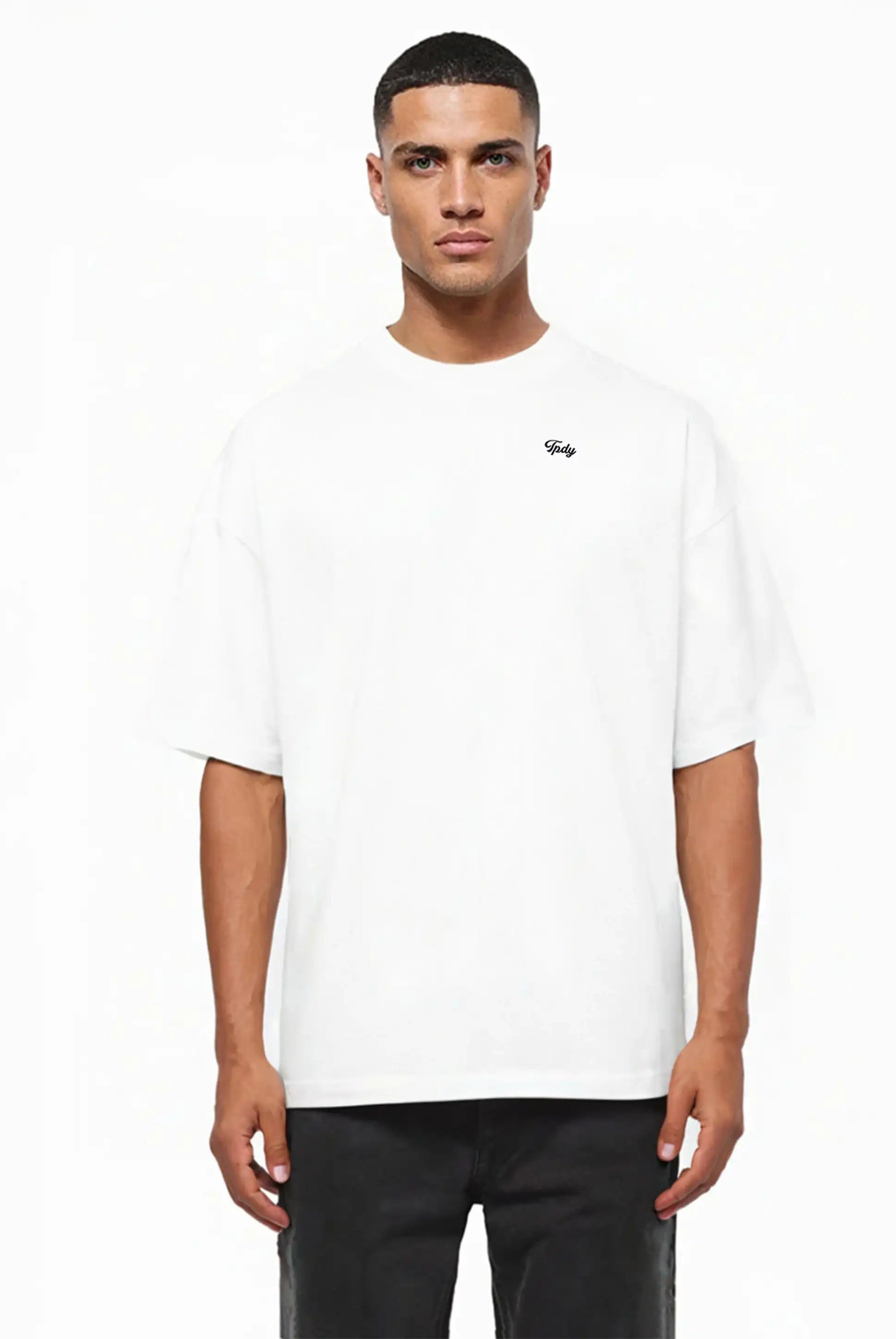 Ein Mann steht mit dem trueprodigy Nika Oversize-Basicshirt mit TPDY-Stickerei & klarer Silhouette, gepaart mit einer schwarzen Hose, vor einem weißen Hintergrund.