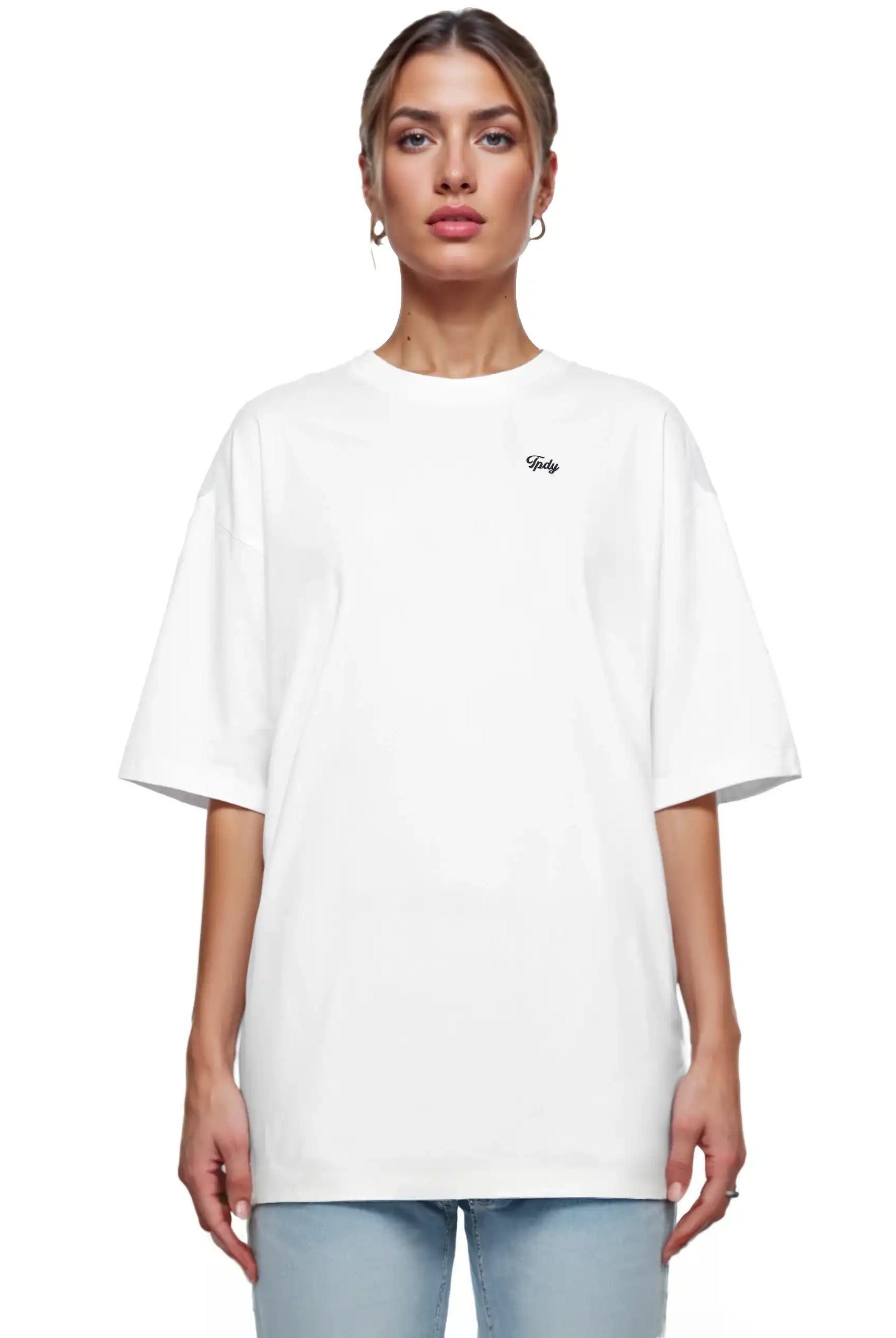 Eine Frau blickt nach vorne in einem trueprodigy Nika F Damen Oversize-T-Shirt mit TPDY-Stickerei auf der Brust und hellblauen Jeans, vor einem schlichten weißen Hintergrund.