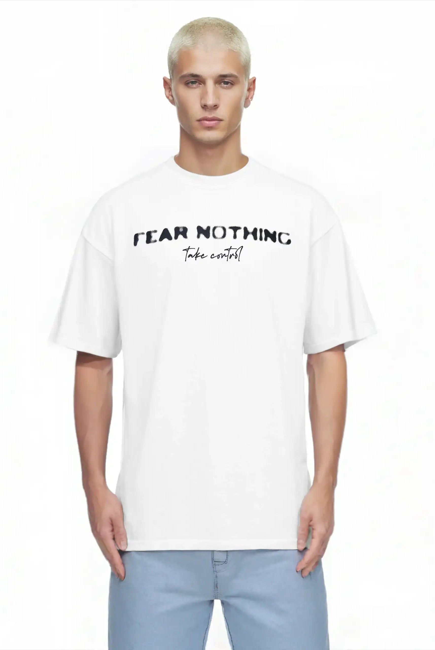 Ein junger Mann mit kurzen blonden Haaren trägt das trueprodigy Noa Oversize-Shirt mit "FEAR NOTHING"-Print & handschriftlichem Detail, gepaart mit hellblauen Jeans, und steht vor einem schlichten weißen Hintergrund.