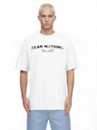 Ein junger Mann mit kurzen blonden Haaren trägt das trueprodigy Noa Oversize-Shirt mit "FEAR NOTHING"-Print & handschriftlichem Detail, gepaart mit hellblauen Jeans, und steht vor einem schlichten weißen Hintergrund.