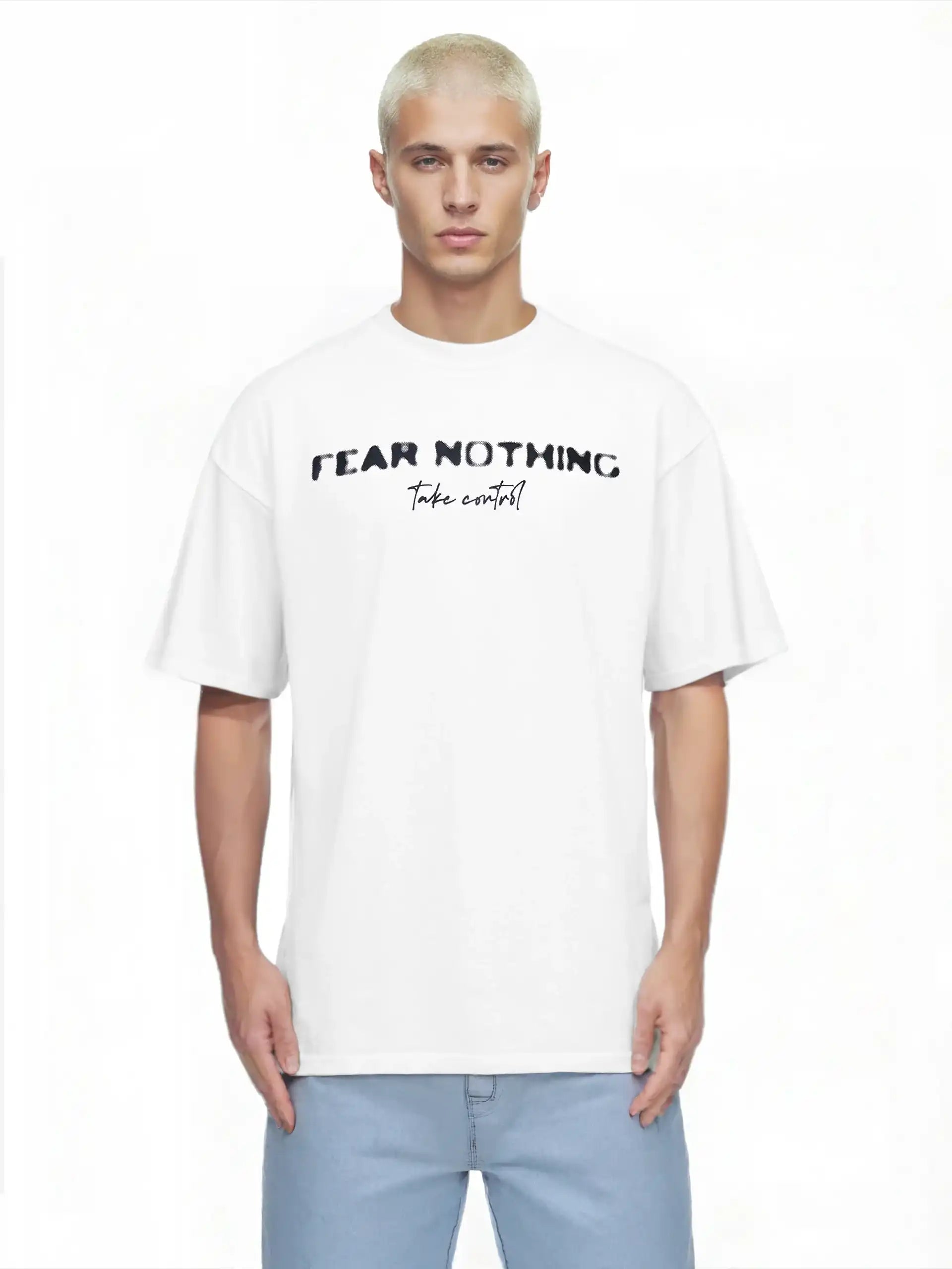 Ein junger Mann mit kurzen blonden Haaren trägt das trueprodigy Noa Oversize-Shirt mit "FEAR NOTHING"-Print & handschriftlichem Detail, gepaart mit hellblauen Jeans, und steht vor einem schlichten weißen Hintergrund.