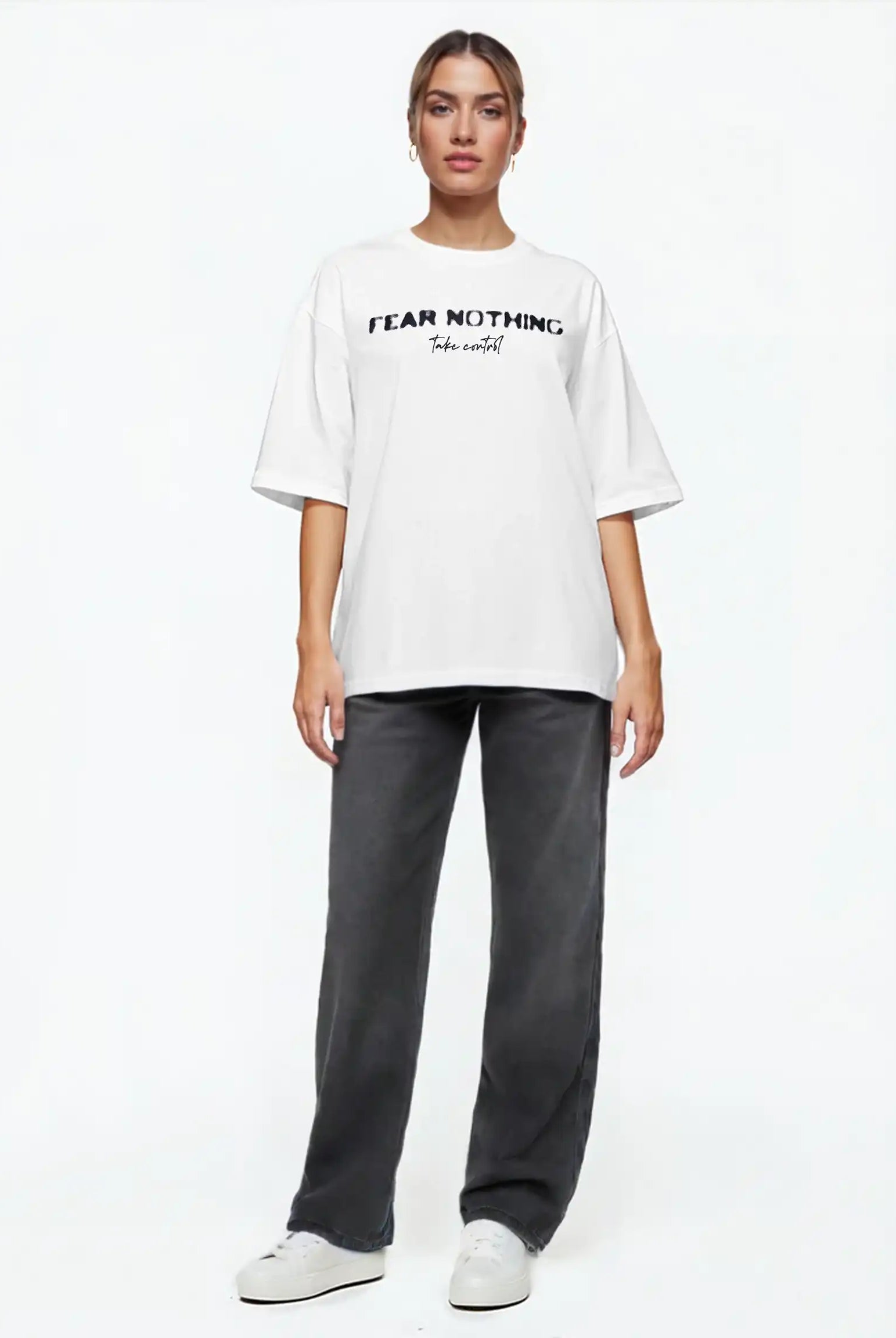 Eine Person steht mit Blick nach vorne in einem trueprodigy Noa F Oversize-T-Shirt mit "FEAR NOTHING" & "take control"-Frontprint, gepaart mit dunkelgrauen Jeans und weißen Turnschuhen, vor einem schlichten weißen Hintergrund.