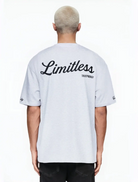 Eine Person mit kurzen, gebleachten blonden Haaren ist von hinten zu sehen und trägt das trueprodigy Kai Oversize-Herren-T-Shirt in Hellgrau mit "LIMITLESS"-Rückenprint und Markenlogo vorn. Der Hintergrund ist einfarbig weiß.