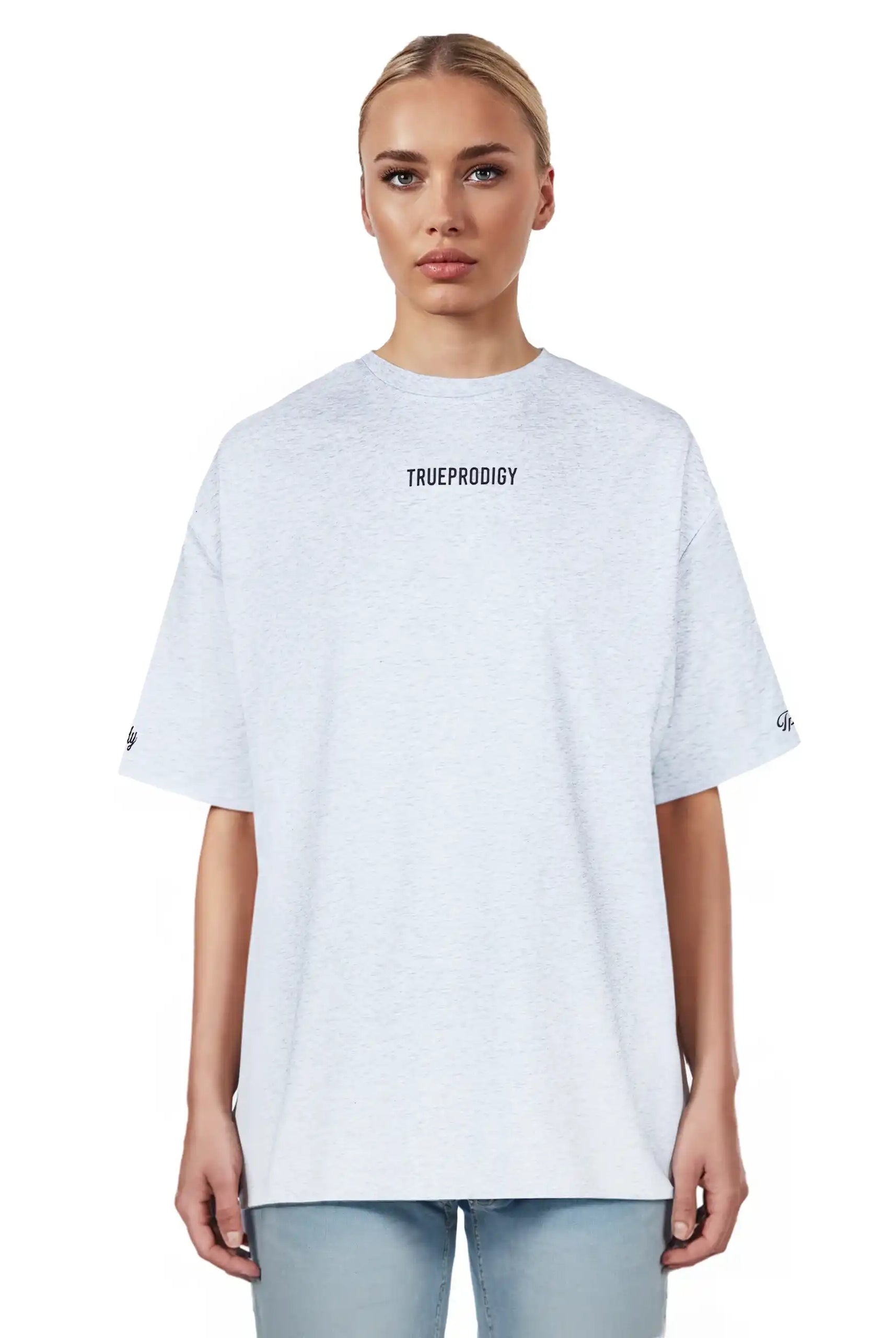 Eine Person mit zurückgebundenen blonden Haaren trägt das trueprodigy Kai F Oversize-Damen-T-Shirt mit "LIMITLESS"-Aufdruck auf dem Rücken und hellblaue Jeans, vor einem schlichten weißen Hintergrund.