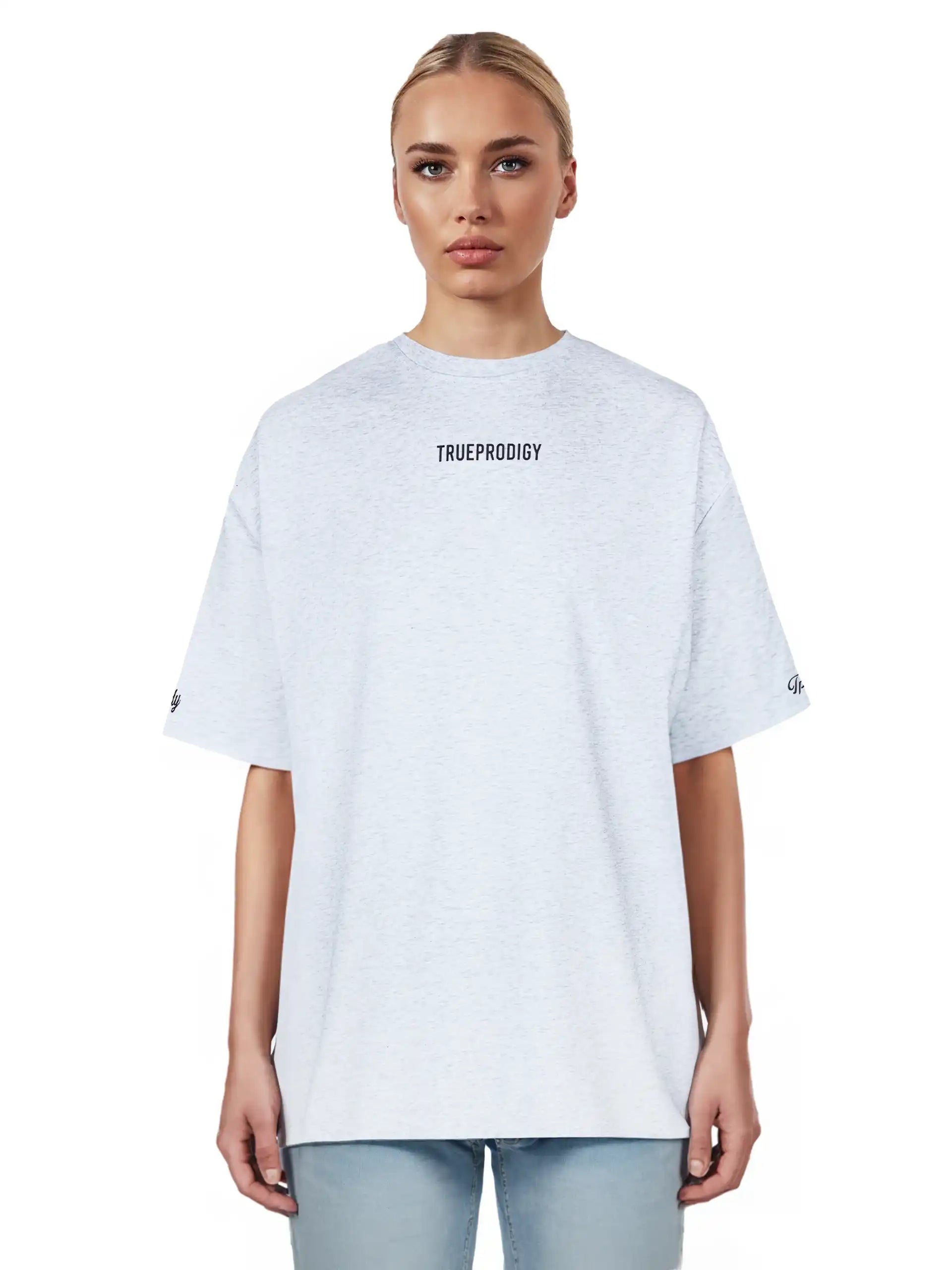 Eine Person mit zurückgebundenen blonden Haaren trägt das trueprodigy Kai F Oversize-Damen-T-Shirt mit "LIMITLESS"-Aufdruck auf dem Rücken und hellblaue Jeans, vor einem schlichten weißen Hintergrund.