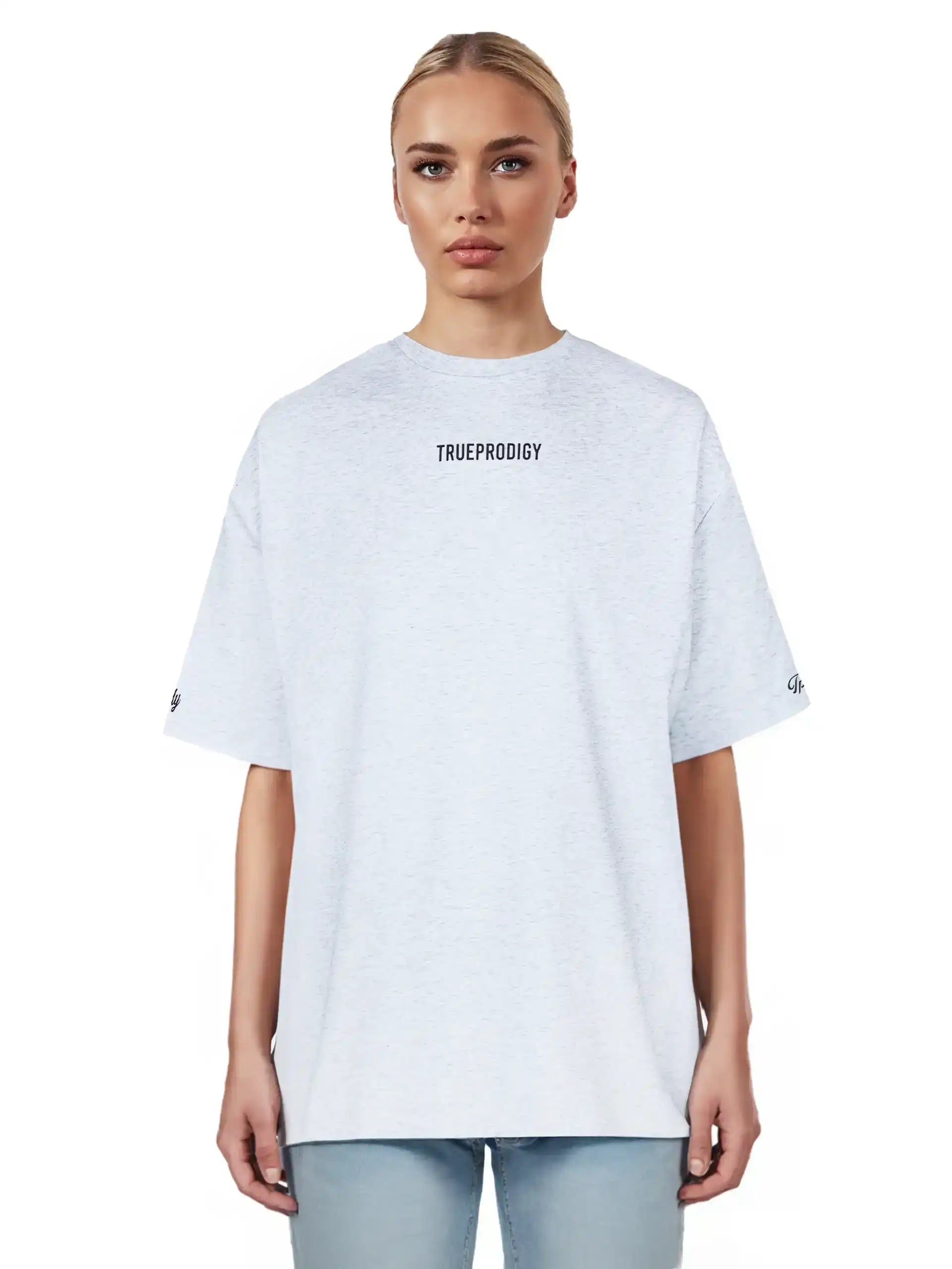 Eine Person mit zurückgebundenen blonden Haaren trägt das trueprodigy Kai F Oversize-Damen-T-Shirt mit "LIMITLESS"-Aufdruck auf dem Rücken und hellblaue Jeans, vor einem schlichten weißen Hintergrund.