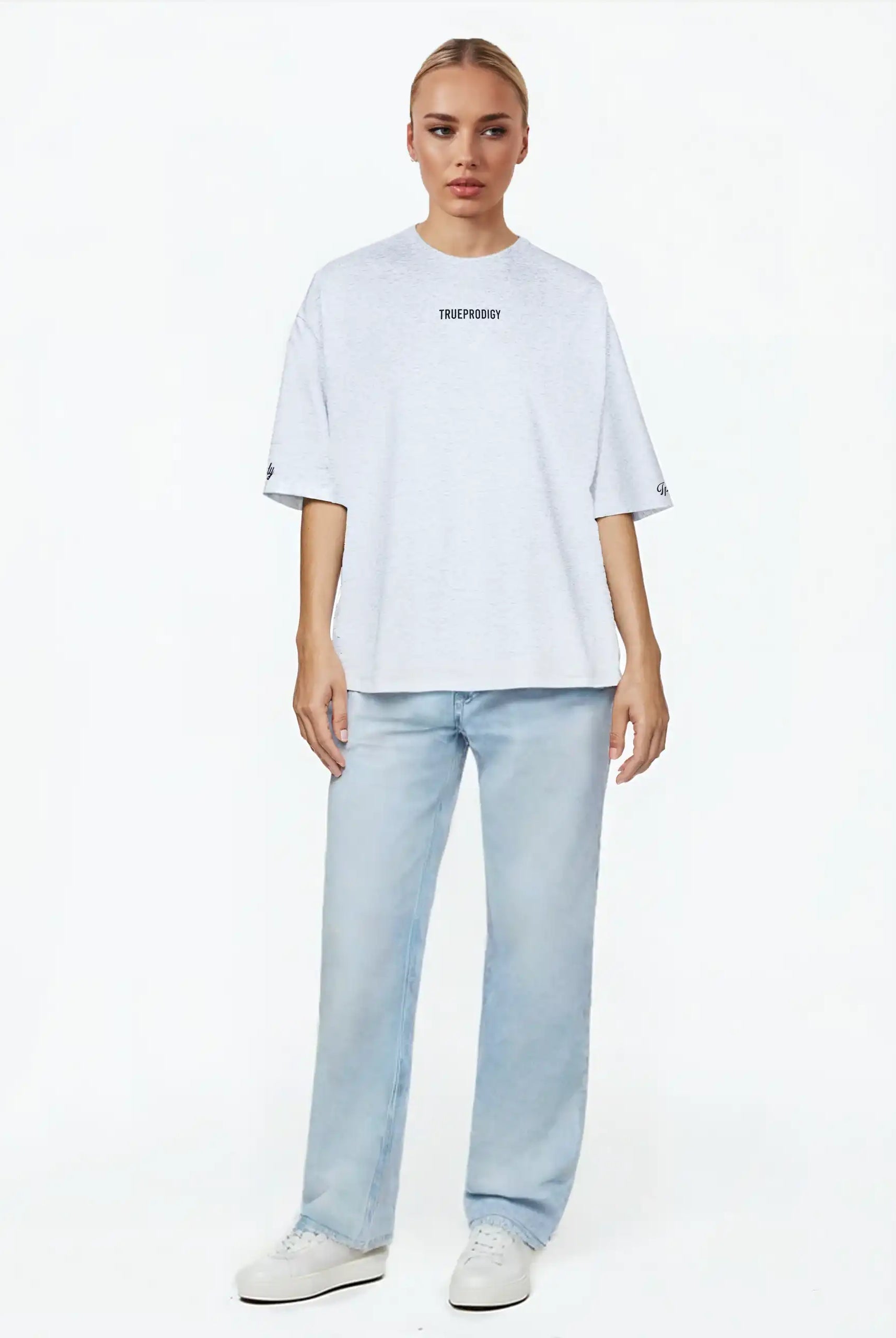 Eine Person blickt nach vorne und trägt das trueprodigy Kai F Oversize-Damen-T-Shirt mit Rückenprint "LIMITLESS", gepaart mit hellblauen Jeans und weißen Turnschuhen, vor einem schlichten weißen Hintergrund.