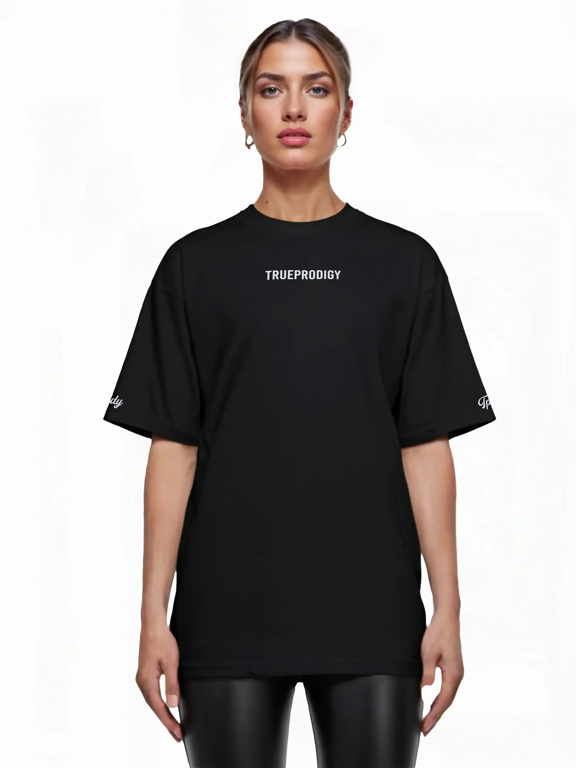 Eine Frau blickt nach vorne und trägt ein schwarzes trueprodigy Kai F Oversize-Damen-T-Shirt mit Rückenprint "LIMITLESS" gepaart mit schwarzen Leggings. Der Hintergrund ist einfarbig weiß.
