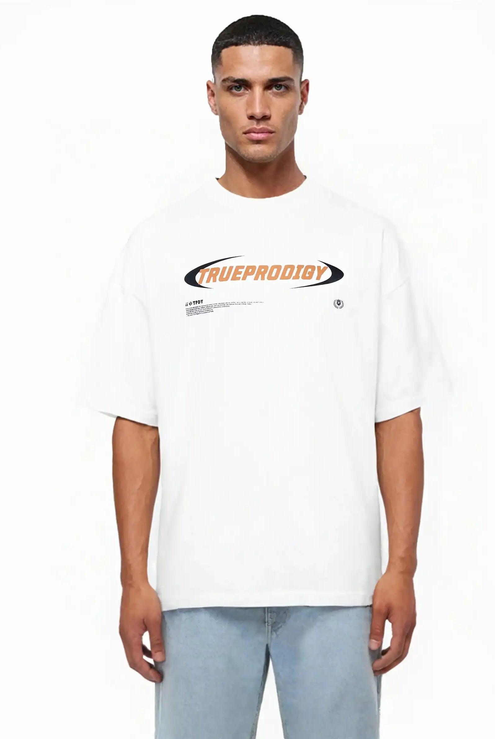 Ein Mann blickt nach vorne und trägt das trueprodigy "Ravi Oversize-Shirt mit großem trueprodigy-Schriftzug vorn" in Weiß mit auffälligem orange-schwarzem Branding auf der Brust, gestylt mit hellblauen Jeans.