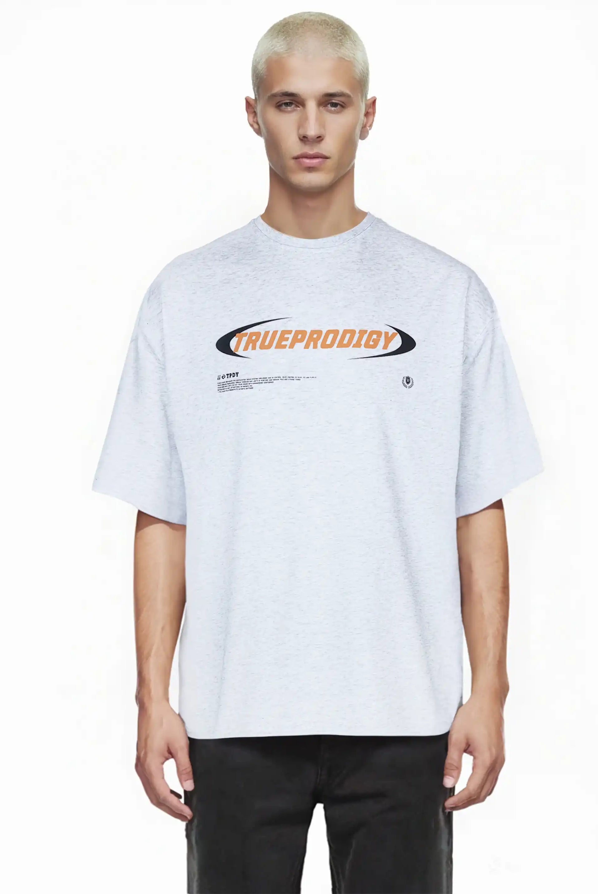Eine Person mit kurzen gebleichten Haaren trägt das trueprodigy Ravi Oversize-Shirt mit großem trueprodigy-Schriftzug vorn in hellgrau und schwarzer Hose. Das locker geschnittene Unisex-Shirt ist aus schwerem Jersey-Stoff gefertigt. Hintergrund: einfarbig weiß.