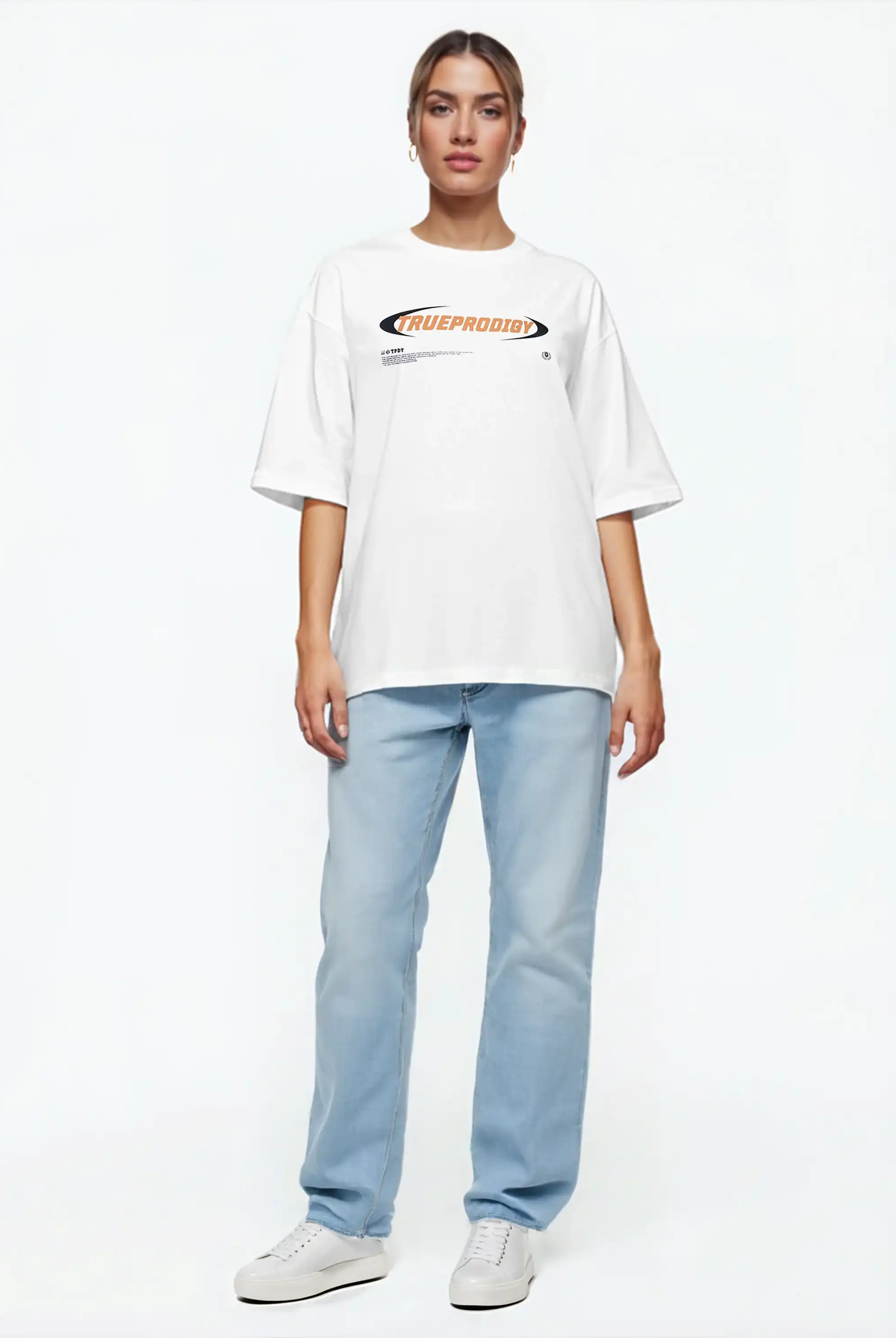 Eine Person steht vor einem schlichten weißen Hintergrund, trägt das trueprodigy Ravi F Oversize-T-Shirt mit farbigem TRUEPRODIGY-Frontprint, hellblaue Jeans und weiße Turnschuhe, die Arme an der Seite und einen neutralen Gesichtsausdruck.