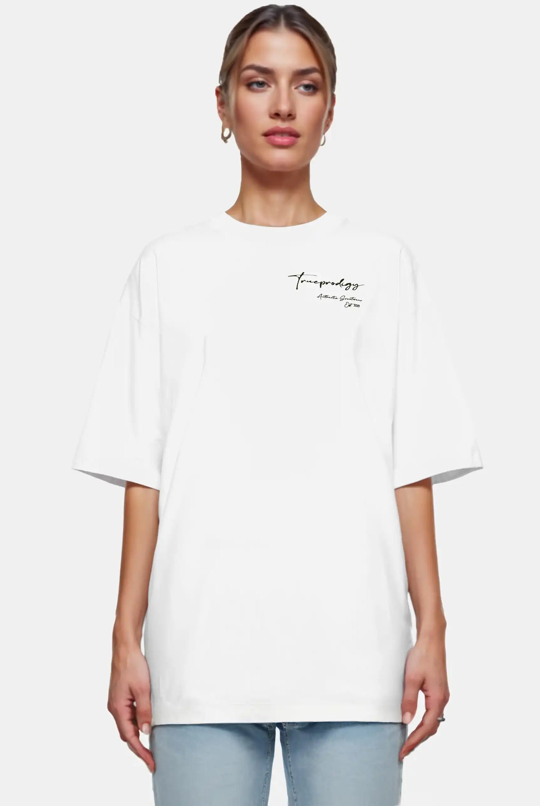 Eine Frau mit hellen, nach hinten gezogenen Haaren blickt in Blue Jeans nach vorne und trägt das trueprodigy Marin F Oversize-T-Shirt mit feiner Logo-Schrift & TPDY-Print am Ärmel vor einem schlichten weißen Hintergrund.