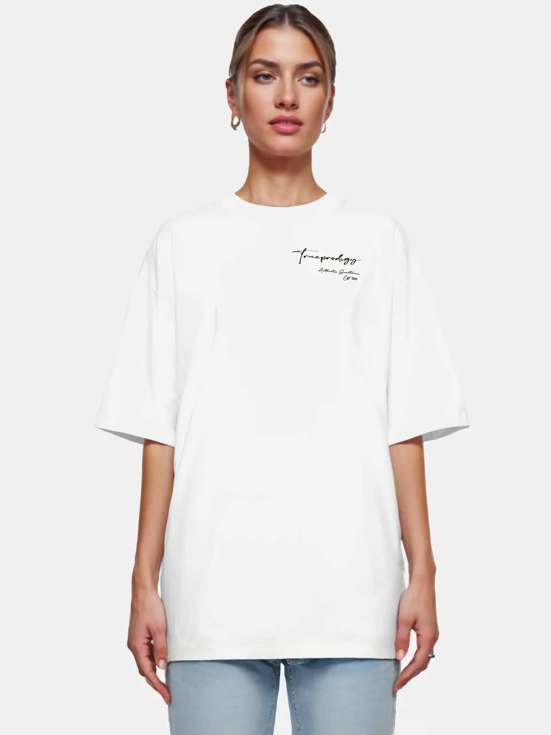 Eine Frau mit hellen, nach hinten gezogenen Haaren blickt in Blue Jeans nach vorne und trägt das trueprodigy Marin F Oversize-T-Shirt mit feiner Logo-Schrift & TPDY-Print am Ärmel vor einem schlichten weißen Hintergrund.