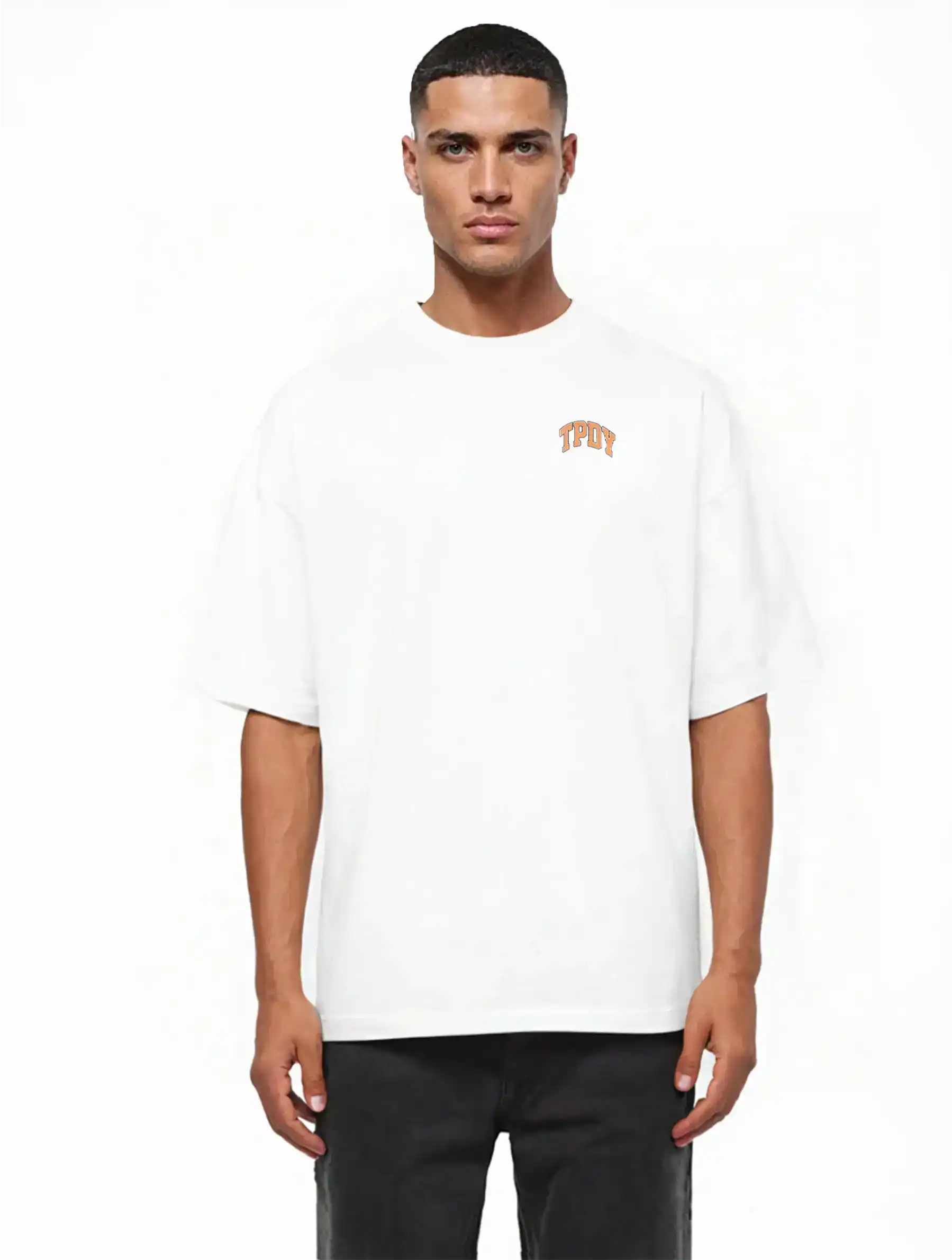 Eine Person mit kurzen dunklen Haaren steht mit dem Blick nach vorne und trägt das trueprodigy Arin Oversize-Shirt mit TPDY-Logo & Rückenprint "Stay Real" in dickem Jersey-Stoff und schwarzer Hose, vor einem schlichten weißen Hintergrund.