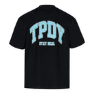 Das Arin Oversize-Shirt von trueprodigy ist ein schwarzes Unisex-T-Shirt aus dickem Jersey-Stoff, mit großem hellblauem TPDY-Schriftzug und weißem "Stay Real"-Print auf dem Rücken.