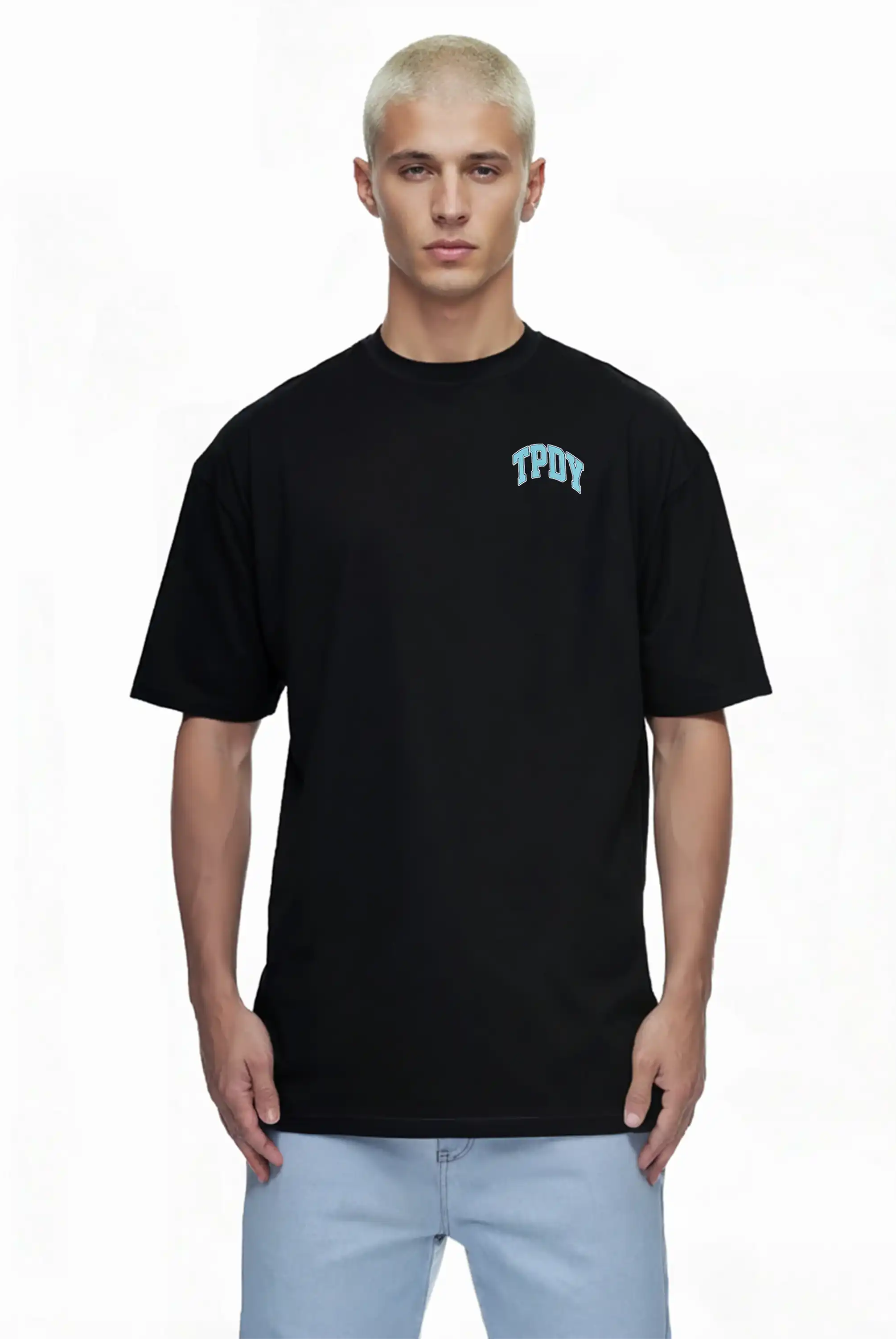 Eine Person mit kurzen, gebleichten blonden Haaren trägt das trueprodigy Arin Oversize-Shirt mit TPDY-Logo & Rückenprint "Stay Real" gepaart mit hellblauen Jeans, stehend vor einem weißen Hintergrund.