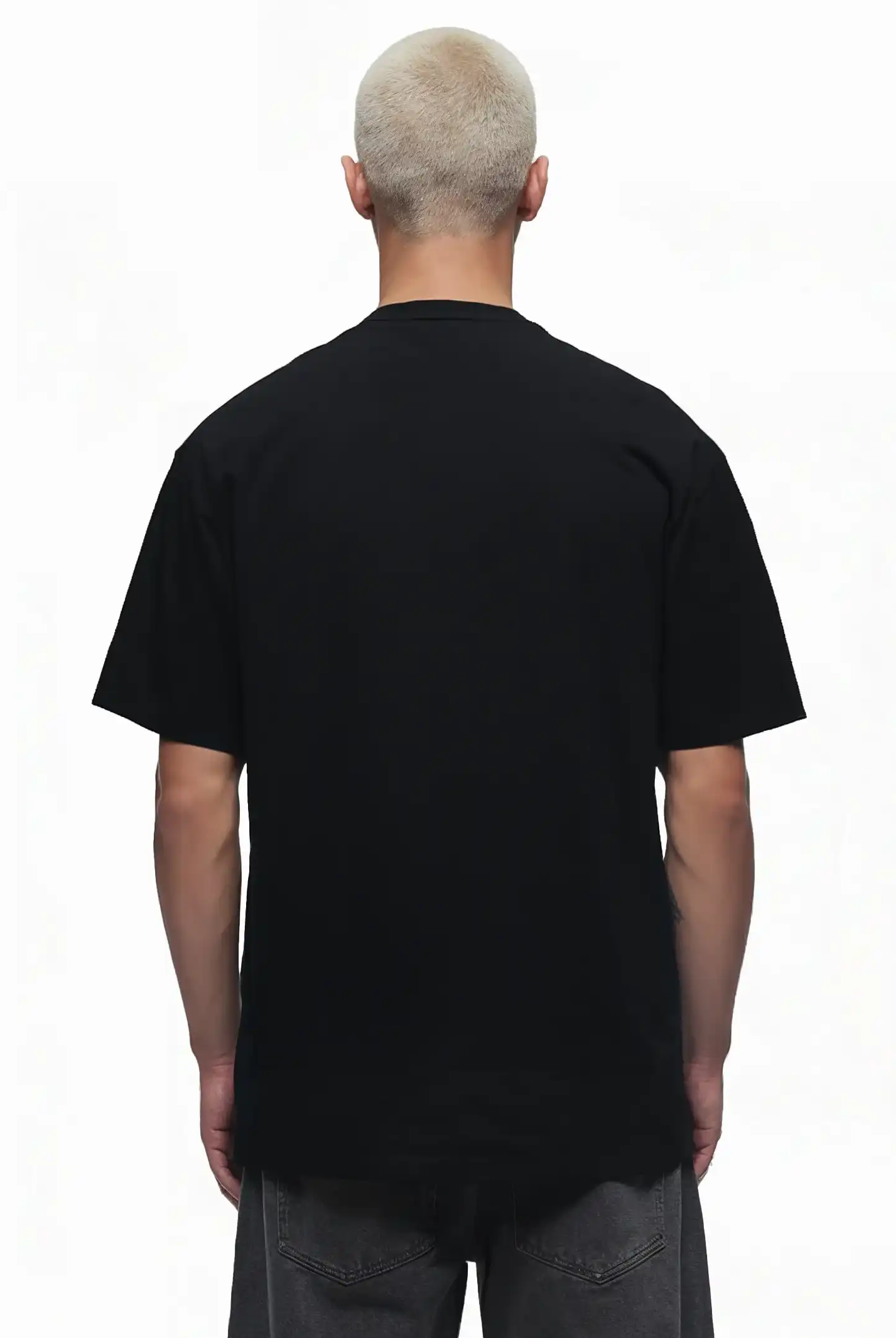 Eine Person mit kurzen, gebleichten Haaren steht mit dem Rücken zur Kamera, trägt das trueprodigy Toni Oversize-Shirt mit 3D-Schaumprint & "Rise Above Limits" und eine dunkelgraue Hose vor weißem Hintergrund.