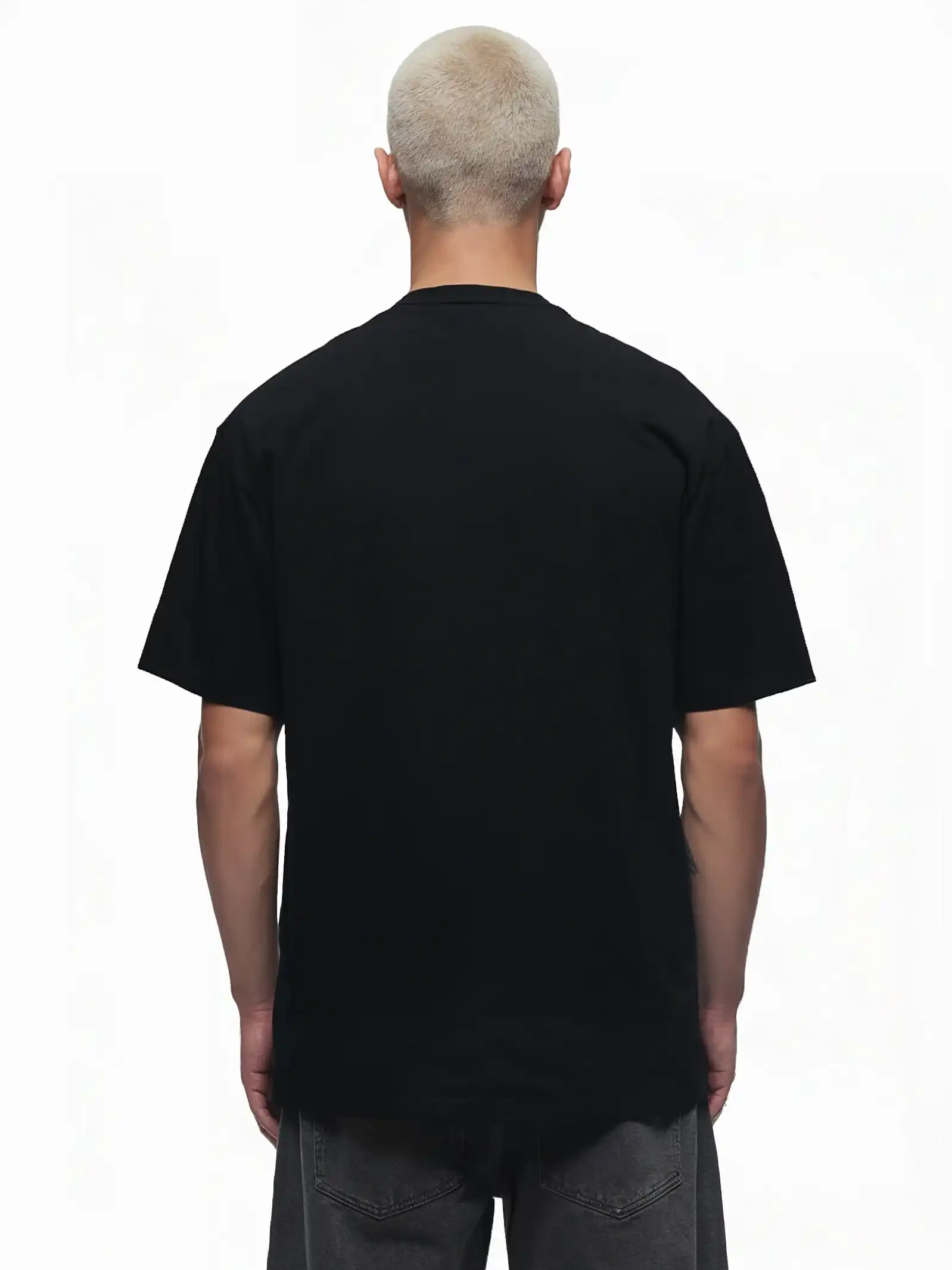 Eine Person mit kurzen, gebleichten Haaren steht mit dem Rücken zur Kamera, trägt das trueprodigy Toni Oversize-Shirt mit 3D-Schaumprint & "Rise Above Limits" und eine dunkelgraue Hose vor weißem Hintergrund.