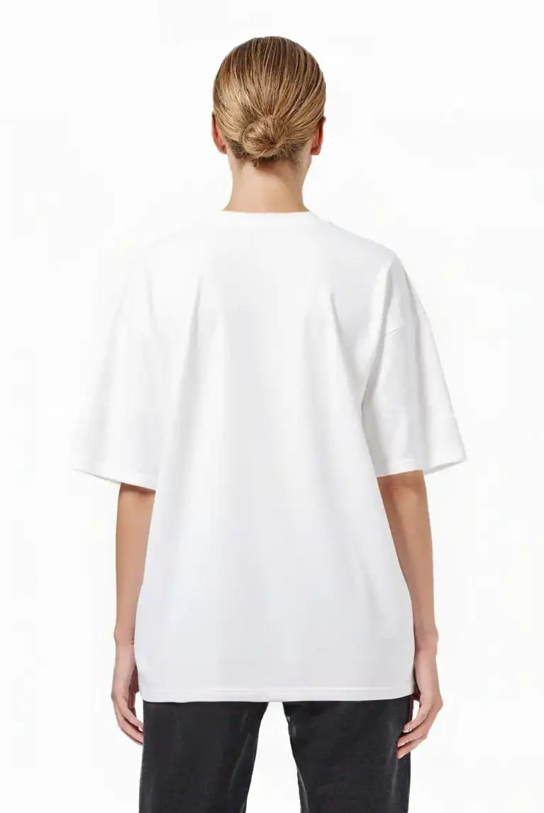 Eine Person mit hellbraunen Haaren in einem tiefen Dutt ist von hinten zu sehen. Sie trägt das trueprodigy Toni F Oversize-T-Shirt mit 3D-Schriftzug "TRUEPRODIGY" & "Rise Above Limits" und eine schwarze Hose vor einem schlichten weißen Hintergrund.