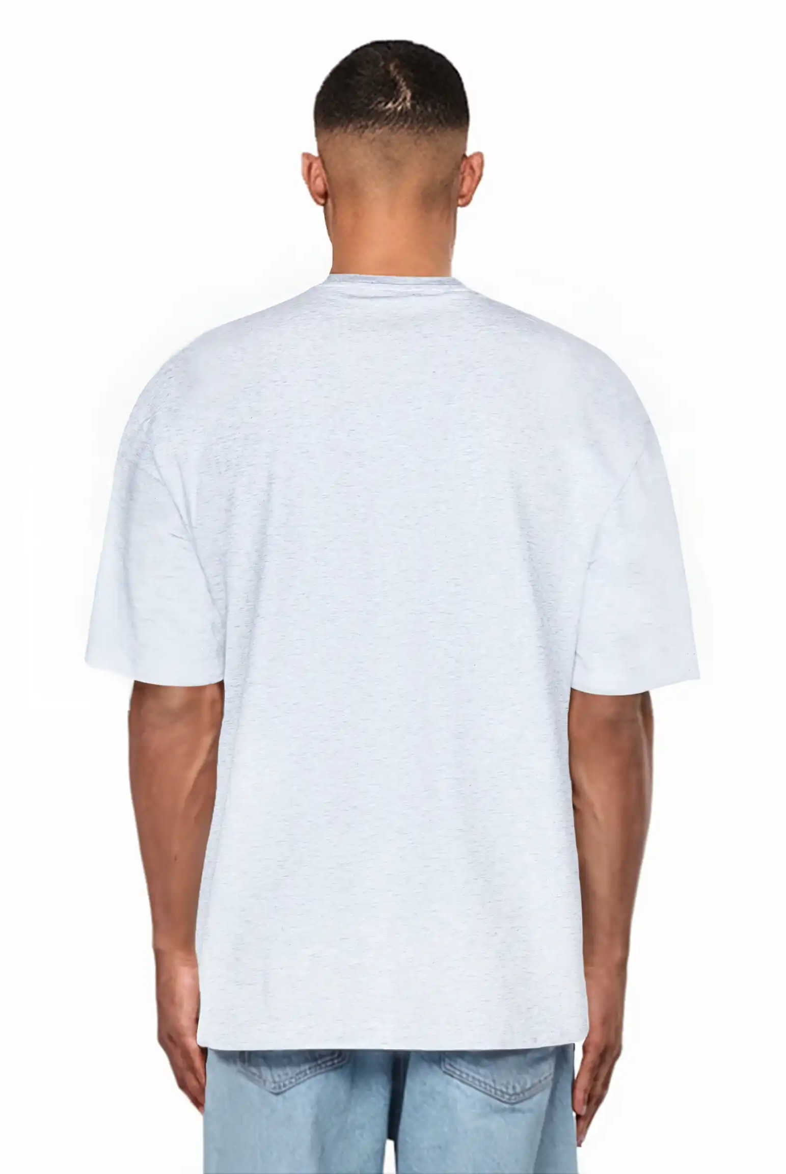 Ein Mann, der mit dem Rücken zur Kamera steht, trägt ein hellgraues trueprodigy Juniper Oversize-Herren-T-Shirt mit Logo-Smile-Grafik auf der Brust und hellblaue Denim-Shorts vor einem schlichten weißen Hintergrund.