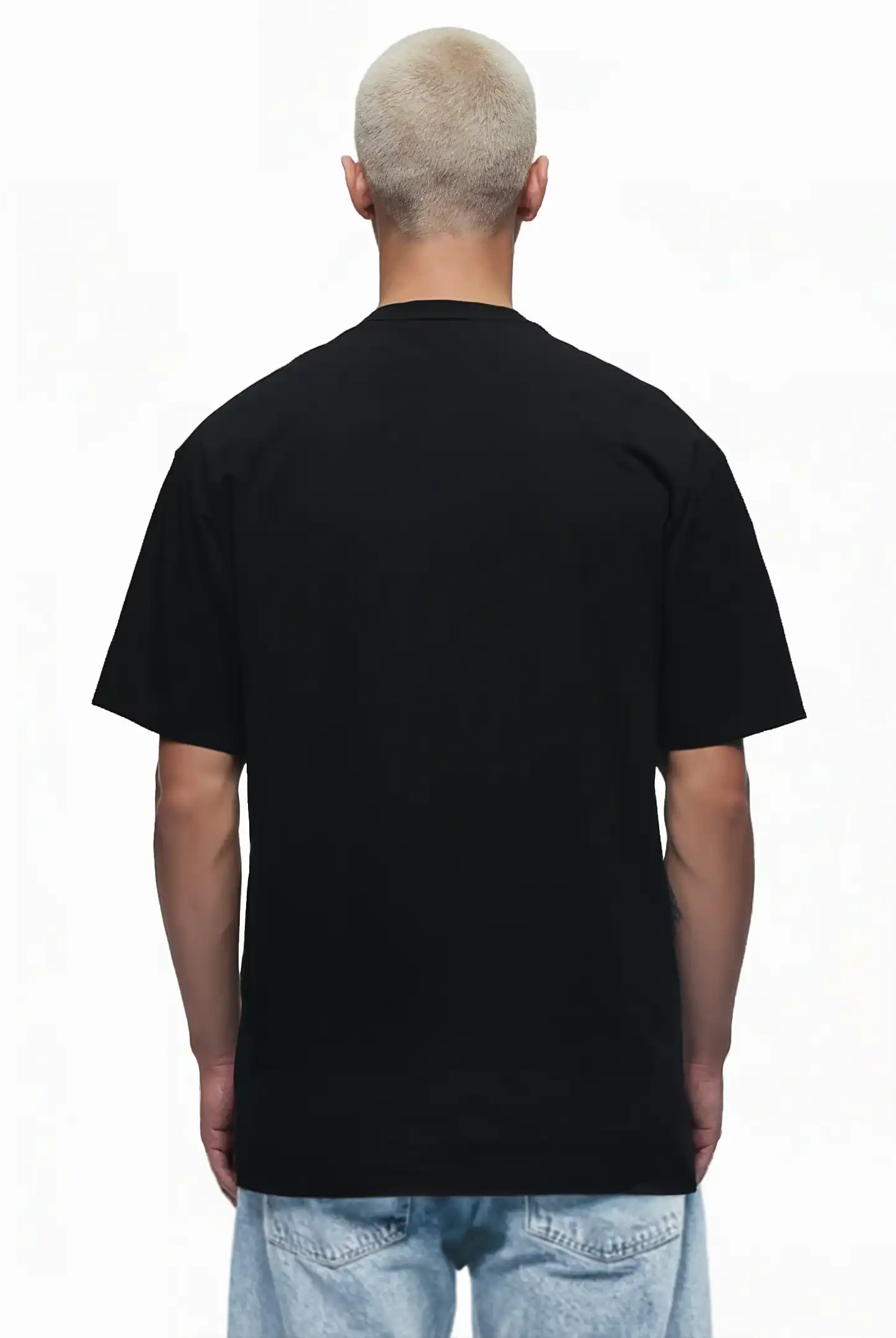 Eine Person mit kurzen, hellblonden Haaren steht mit dem Rücken zur Kamera, trägt das trueprodigy Juniper Oversize-Herren-T-Shirt mit Logo-Smile-Grafik auf der Brust und hellblaue Jeans vor weißem Hintergrund.