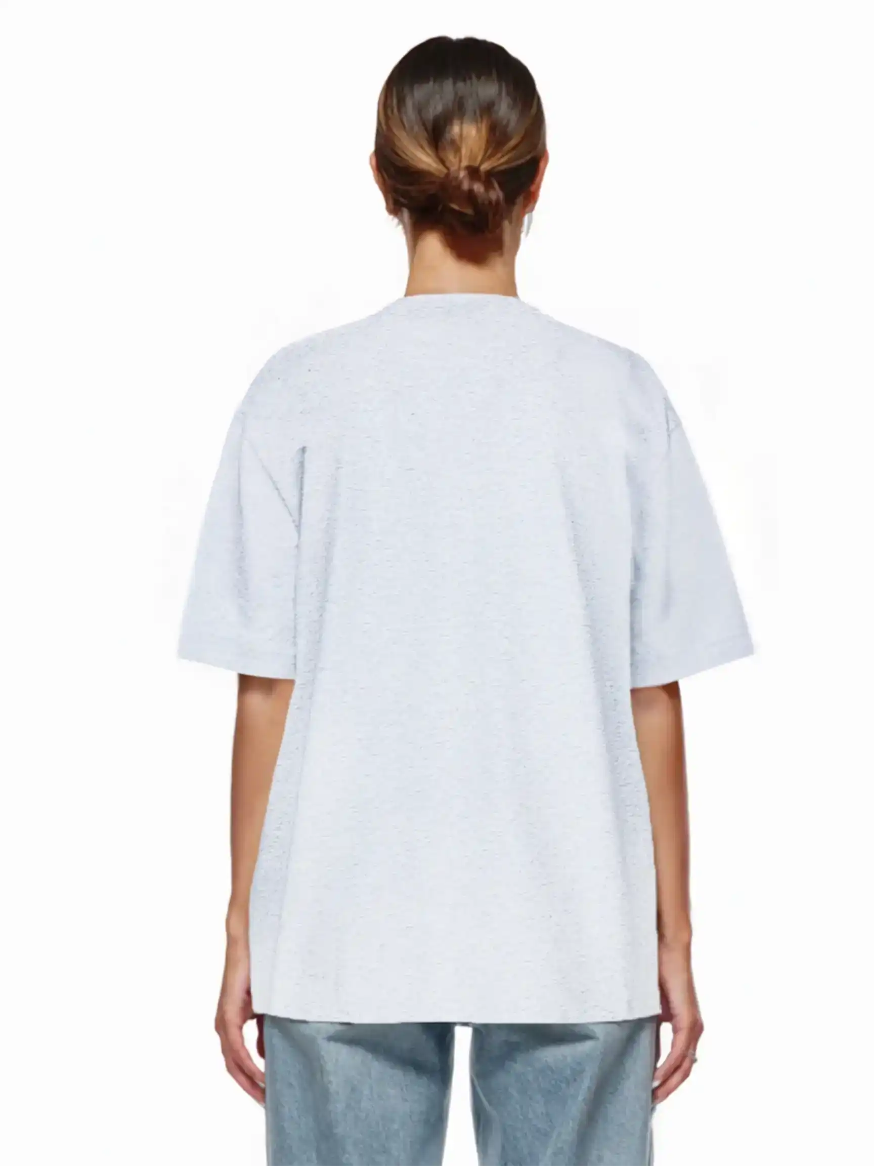 Eine Person mit braunen Haaren in einem tiefen Dutt steht mit dem Rücken zur Kamera, trägt das trueprodigy Juniper F Oversize-Damen-T-Shirt mit Logo-Smile-Grafik und hellblaue Jeans vor einem schlichten weißen Hintergrund.
