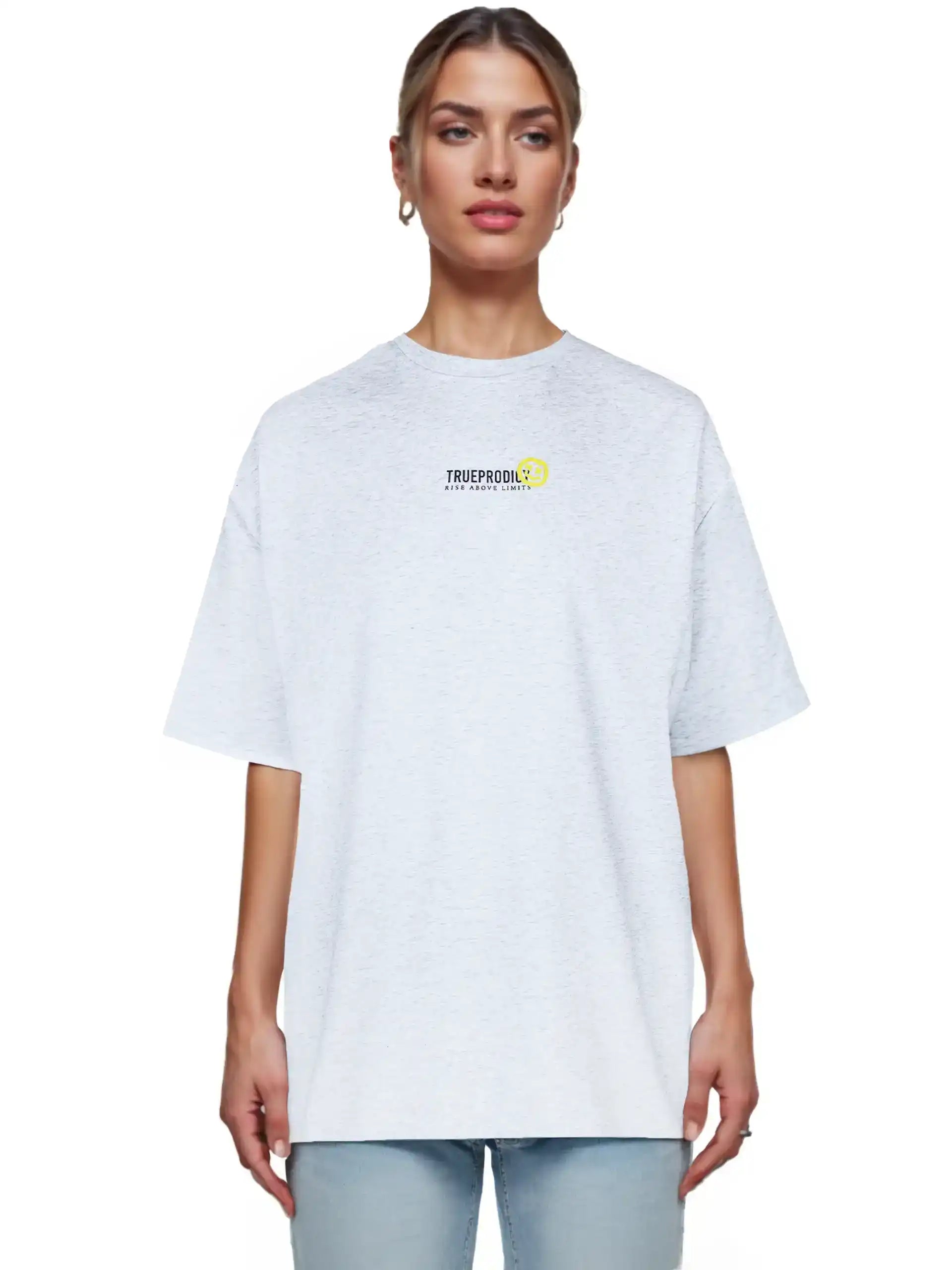 Eine Person blickt nach vorne in einem hellgrauen Juniper F Oversize-Damen-T-Shirt von trueprodigy mit einer kleinen Logo-Smile-Grafik auf der Brust, gepaart mit hellblauen Jeans. Der Hintergrund ist einfarbig weiß.