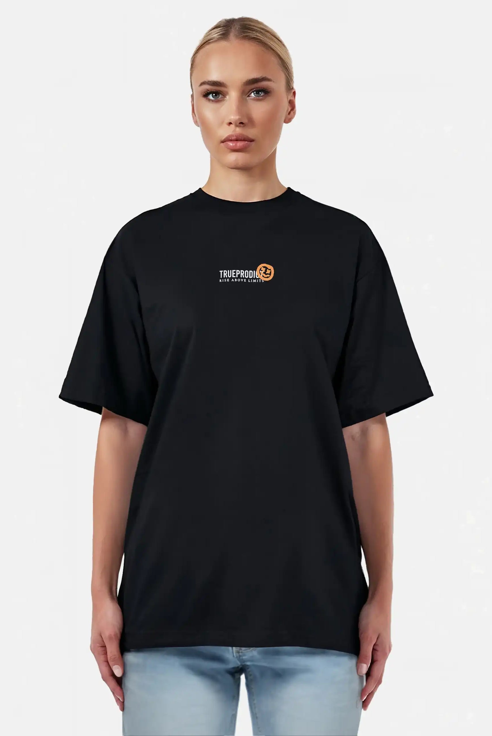 Eine Person mit hellen, zurückgegelten Haaren trägt ein schwarzes trueprodigy Juniper F Oversize-Damen-T-Shirt mit einer Logo-Smile-Grafik auf der Vorderseite, gepaart mit hellblauen Jeans, vor einem schlichten hellen Hintergrund.