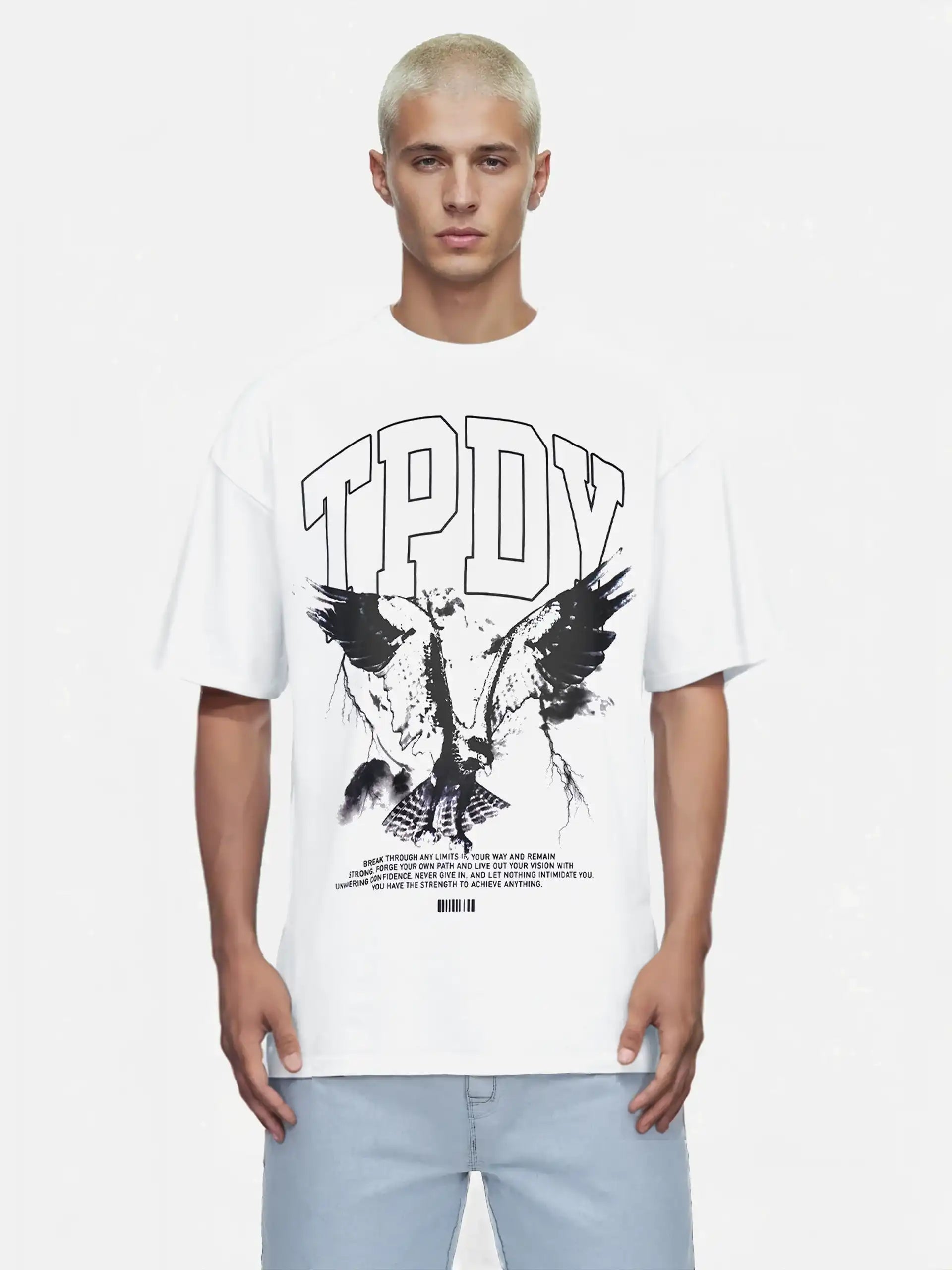 Eine Person mit kurzen blonden Haaren trägt das trueprodigy Yuki Oversize-T-Shirt mit Adlergrafik & TPDY-Schriftzug in weiß, gepaart mit hellblauen Jeans, vor einem schlichten Hintergrund.
