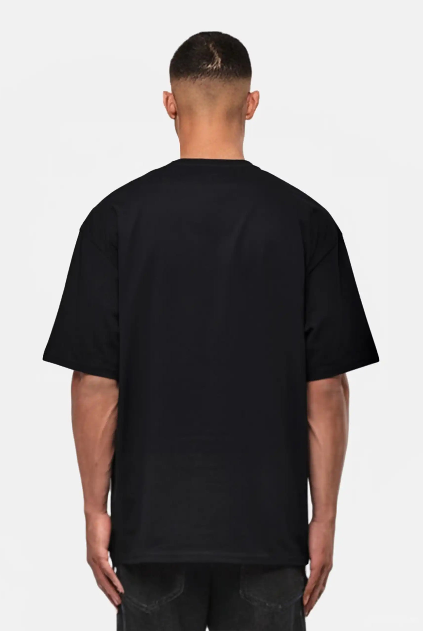 Eine von der Kamera abgewandte Person, die ein trueprodigy Yuki Oversize-T-Shirt mit Adlergrafik & TPDY-Schriftzug und eine dunkle Jeans trägt, steht vor einem weißen Hintergrund.