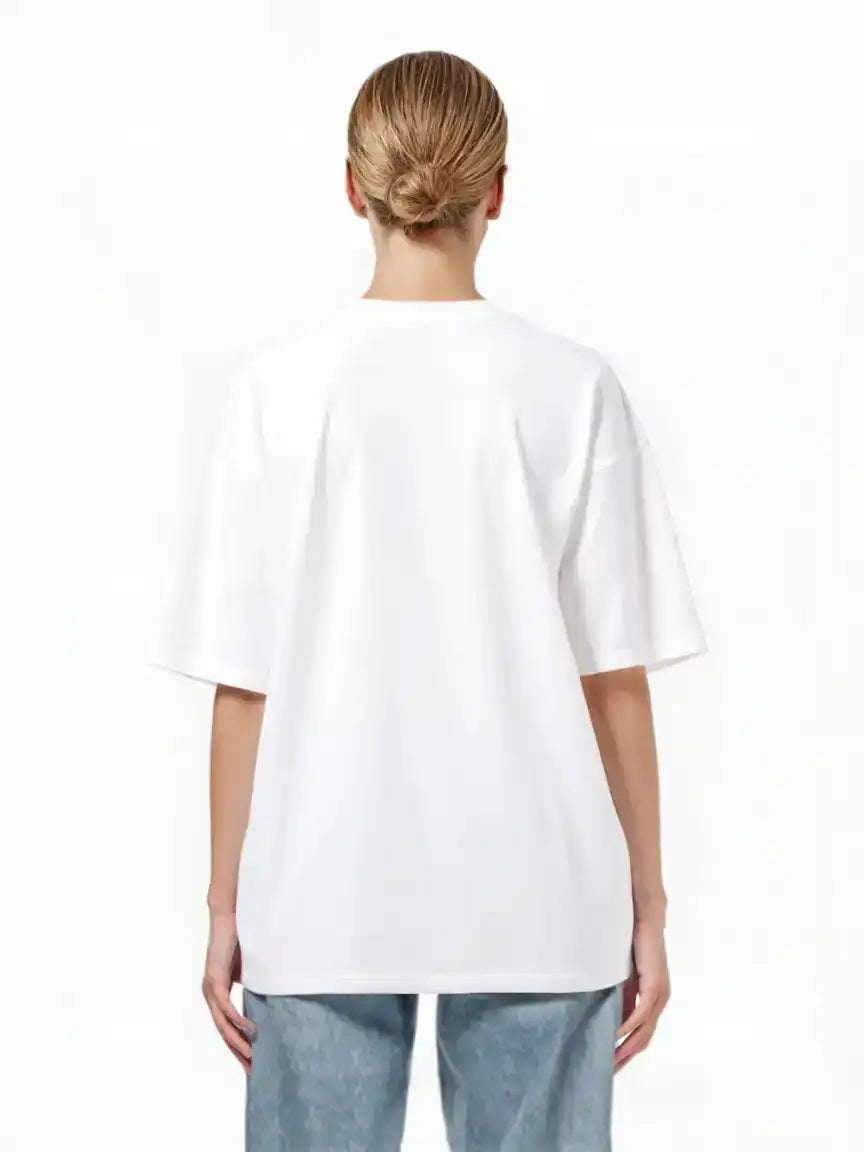 Eine Person mit blonden Haaren in einem tiefen Dutt ist von hinten zu sehen. Sie trägt ein trueprodigy Oversize-T-Shirt mit Adlergrafik & TRUEPRODIGY-Schriftzug und blaue Jeans und steht vor einem schlichten weißen Hintergrund.