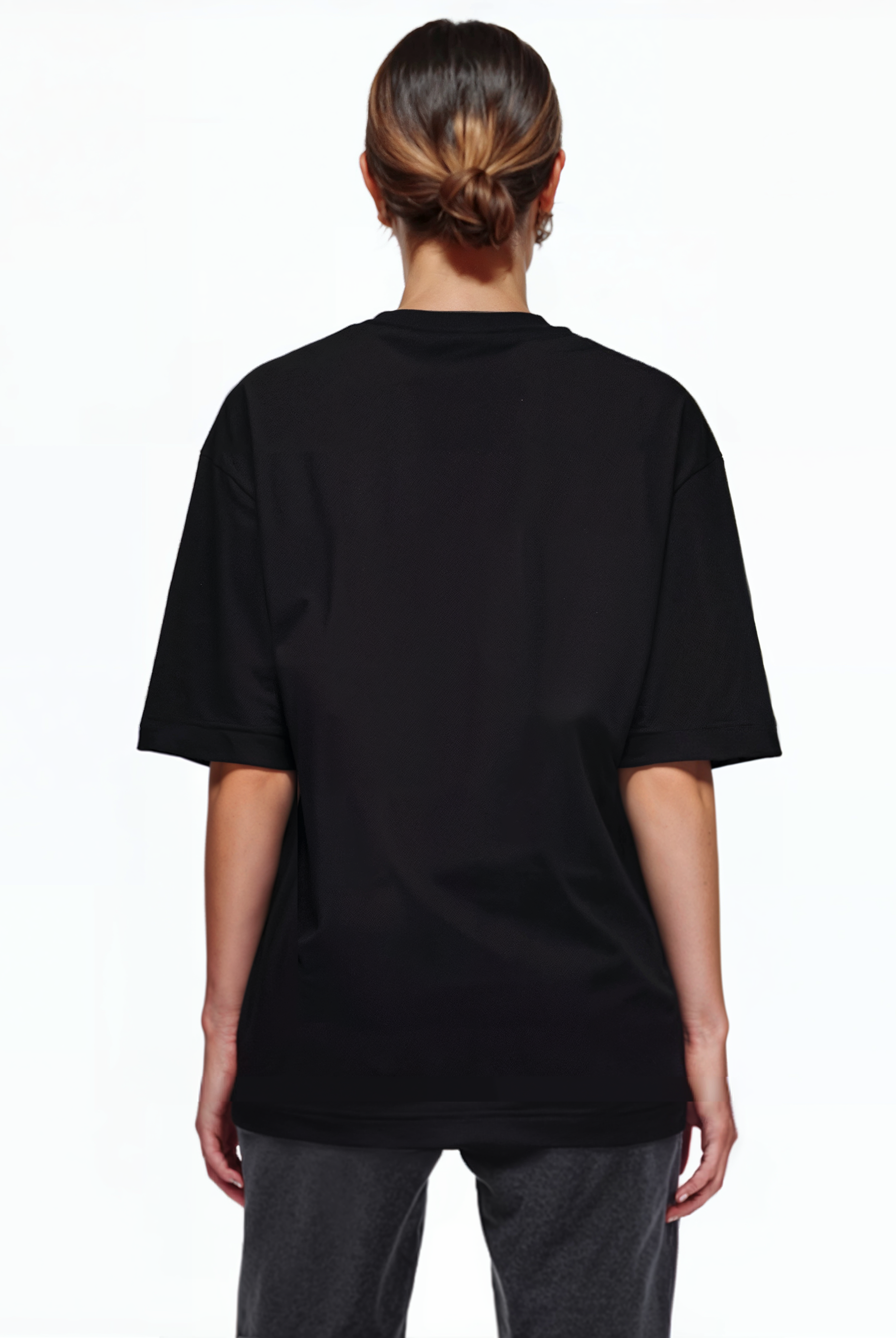 Eine Person mit braunen Haaren in einem tiefen Dutt ist von hinten zu sehen. Sie trägt ein trueprodigy Oversize-T-Shirt mit Adlergrafik & TRUEPRODIGY-Schriftzug und eine dunkle Hose und steht vor einem schlichten weißen Hintergrund.