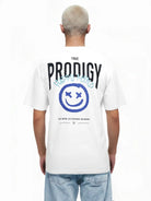 Eine Person mit kurzen, hellen Haaren trägt das trueprodigy Hajin Oversize-T-Shirt mit Sprüh-Smiley, "trueprodigy"-Branding und "Happy Mind"-Aufdruck auf dem Rücken.