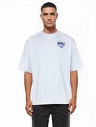 Ein Mann mit kurzen Haaren trägt das trueprodigy Hajin Oversize-T-Shirt mit Spray-Smiley und "Happy Mind"-Rückenprint in Hellgrau, gepaart mit einer schwarzen Hose, vor einem schlichten weißen Hintergrund.