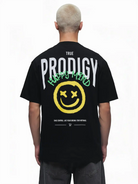 Eine Person mit kurzen, gebleichten Haaren ist von hinten zu sehen, die das trueprodigy Hajin Oversize-T-Shirt mit einem Sprüh-Smiley und dem Aufdruck "Happy Mind" auf dem Rücken trägt.