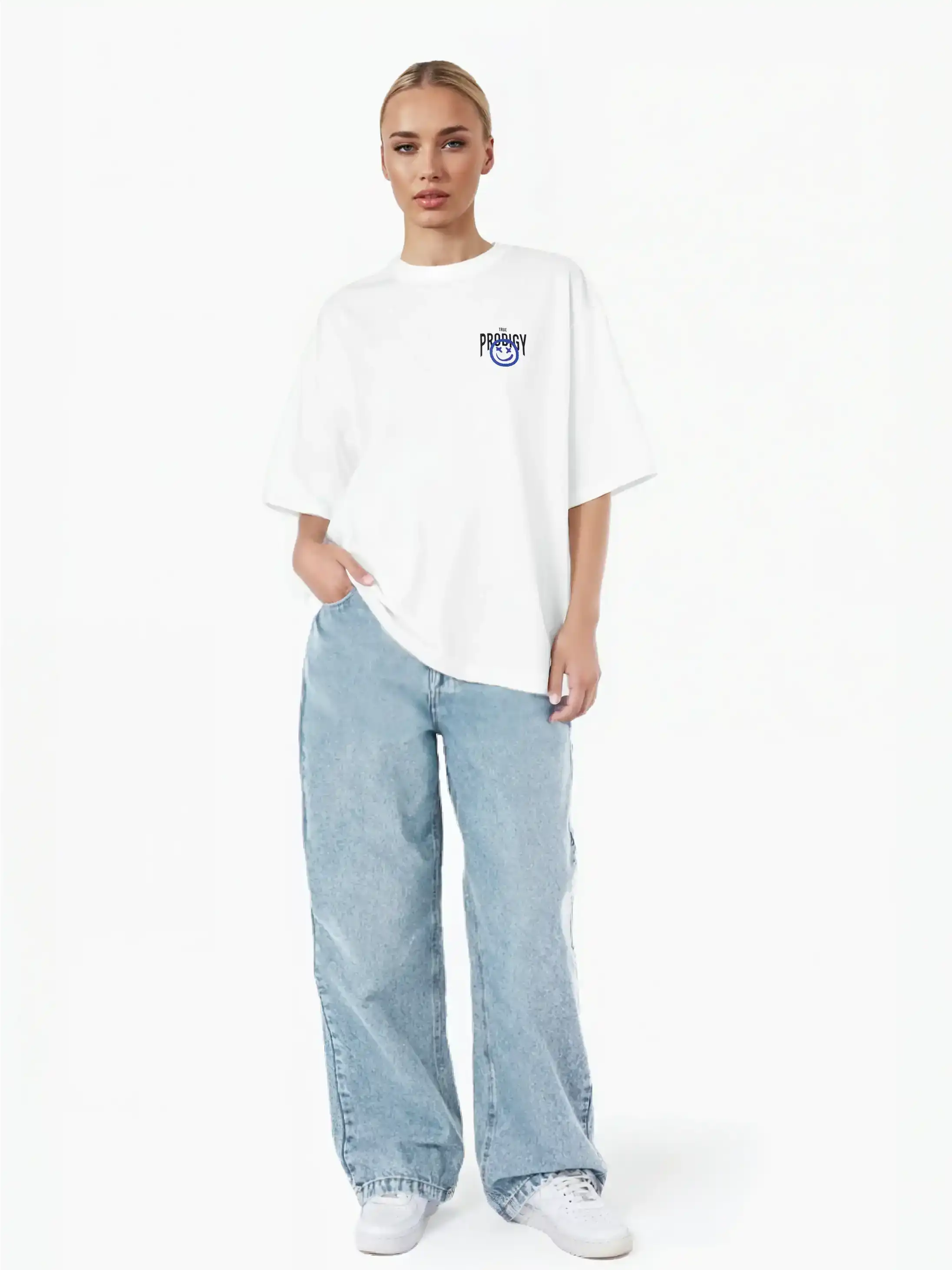 Eine Person steht vor einem weißen Hintergrund und trägt das trueprodigy Hajin F Oversize-T-Shirt mit Spray-Smiley & Happy-Mind-Print, hellblaue Baggy-Jeans und weiße Turnschuhe. Eine Hand steckt in der Tasche.
