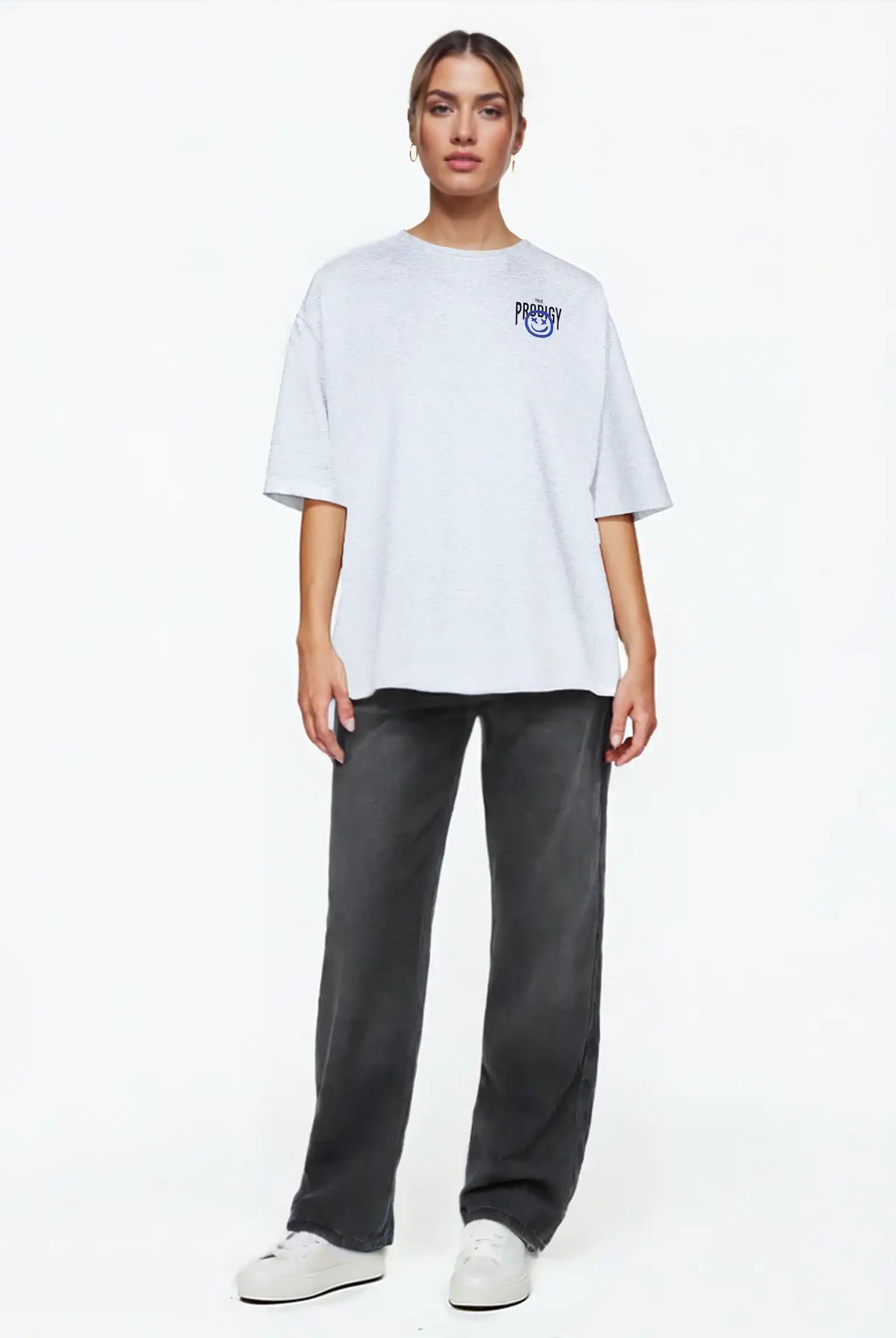 Eine Person steht vor einem weißen Hintergrund, trägt das trueprodigy Hajin F Oversize-T-Shirt mit Spray-Smiley & Happy-Mind-Print, dunkelgraue Jeans und weiße Turnschuhe, blickt nach vorne und hat einen neutralen Blick.