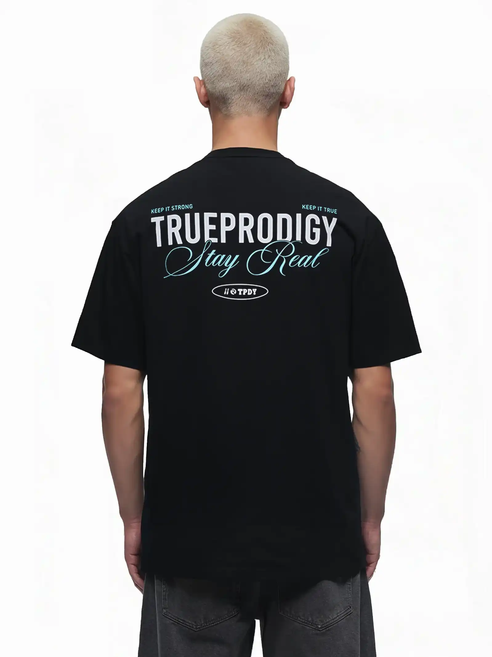 Eine Person mit kurzen blonden Haaren trägt von hinten das trueprodigy Lou Oversize-T-Shirt mit Schriftzug & "Stay Real" Front- & Rückenprint, mit weißem und blauem Druck auf dem oberen Rücken.