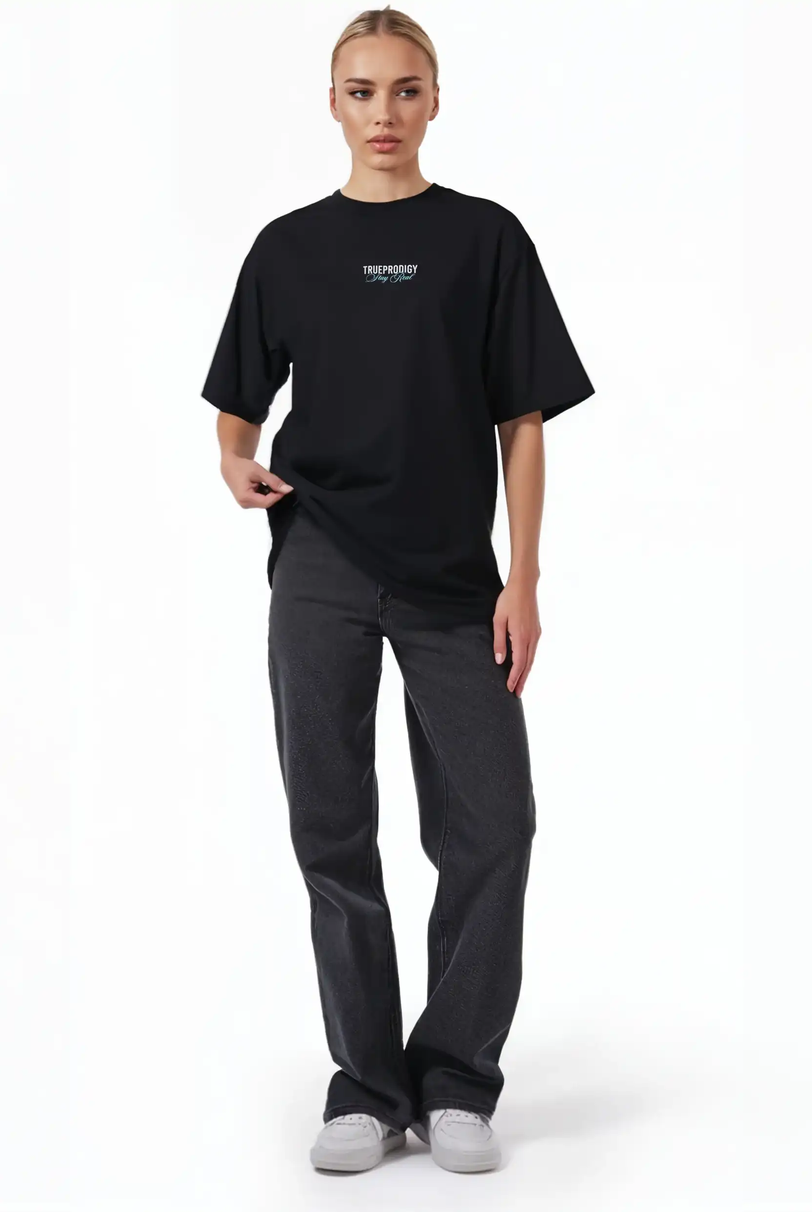 Eine Person steht vor einem schlichten weißen Hintergrund und trägt das trueprodigy Lou F Oversize-T-Shirt mit "Stay Real"-Druck auf Vorder- und Rückseite aus schwerem Jersey, gepaart mit einer dunklen Jeans und weißen Sneakers. Das Unisex-Shirt hat eine kleine Brustgrafik.