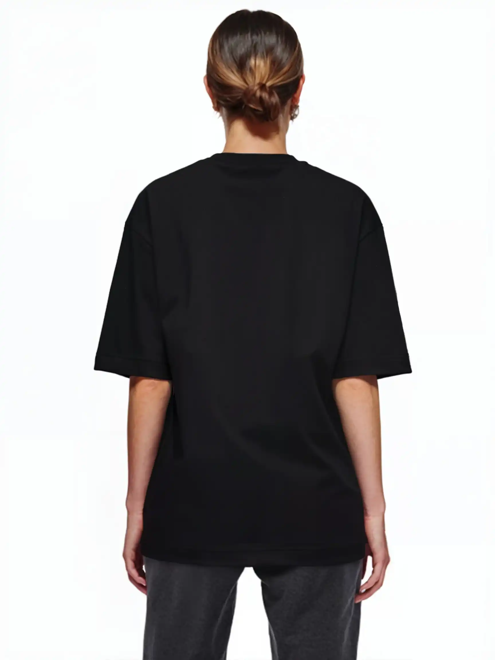 Eine Person schaut von der Kamera weg und trägt das trueprodigy Jamie F Oversize-T-Shirt mit Skulptur-Grafik, Schlange & "Fear Nothing"-Print in schwarz mit dunkelgrauer Hose. Ihre Haare sind vor einem schlichten weißen Hintergrund nach hinten gezogen.