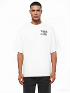 Ein Mann mit kurzen Haaren und neutralem Gesichtsausdruck trägt das trueprodigy Alex Oversize-T-Shirt, das auf der Vorder- und Rückseite mit skizzierten Rosen und dem Markenlogo bedruckt ist, vor einem schlichten weißen Hintergrund.