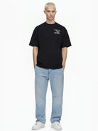 Eine Person mit kurzen blonden Haaren blickt nach vorne und trägt das trueprodigy Alex Oversize-T-Shirt mit Rosen-Skizze & trueprodigy-Logo als Front- & Rückenprint, hellblaue Jeans und weiße Turnschuhe auf einem schlichten weißen Hintergrund.