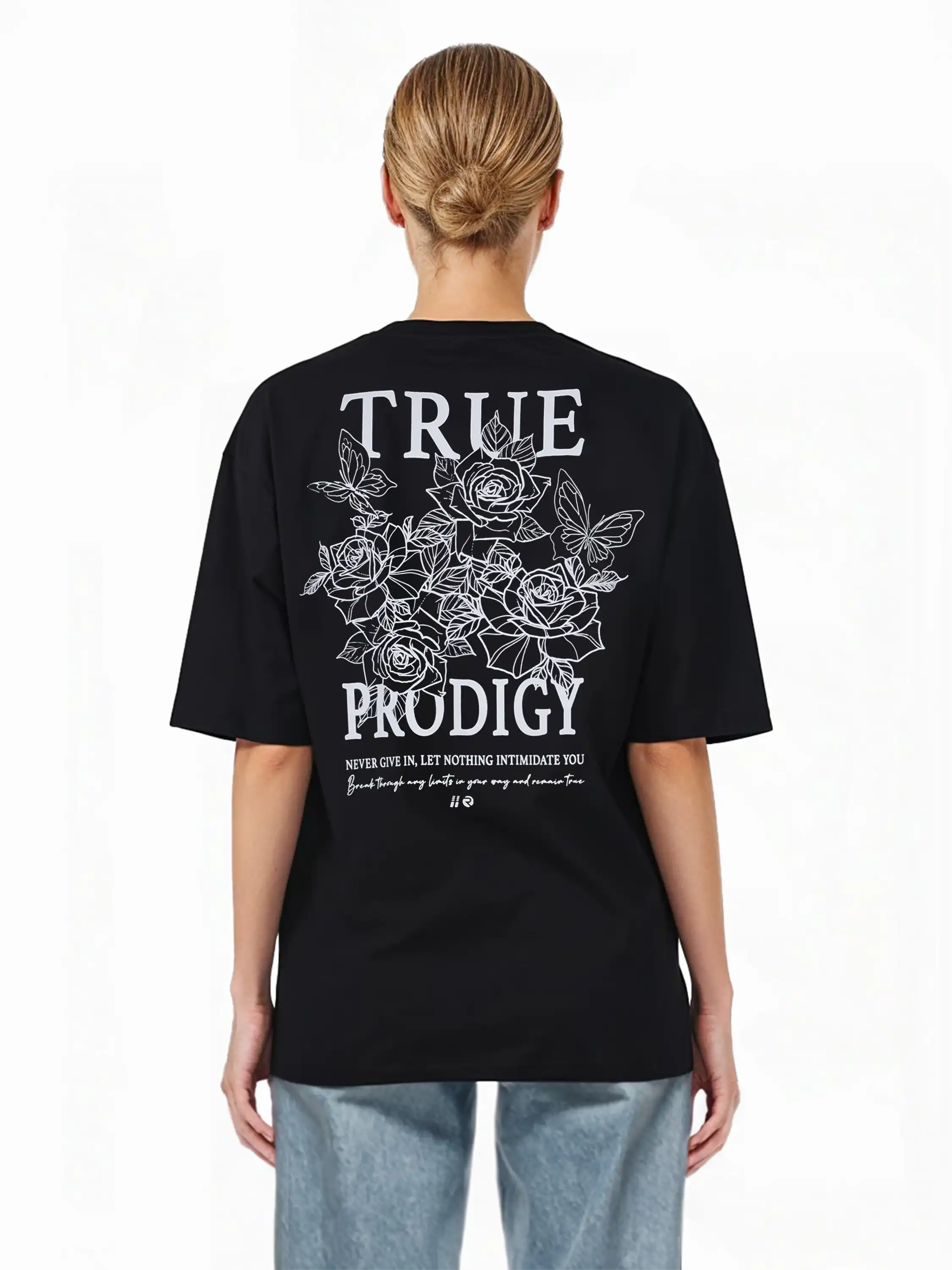 Eine Person mit hellen Haaren in einem tiefen Dutt trägt das schwarze trueprodigy Alex F Oversize-T-Shirt mit einem Spray-Smiley und trueprodigy-Schriftzug auf Vorder- und Rückseite, gepaart mit hellblauen Jeans. Der Hintergrund ist weiß.
